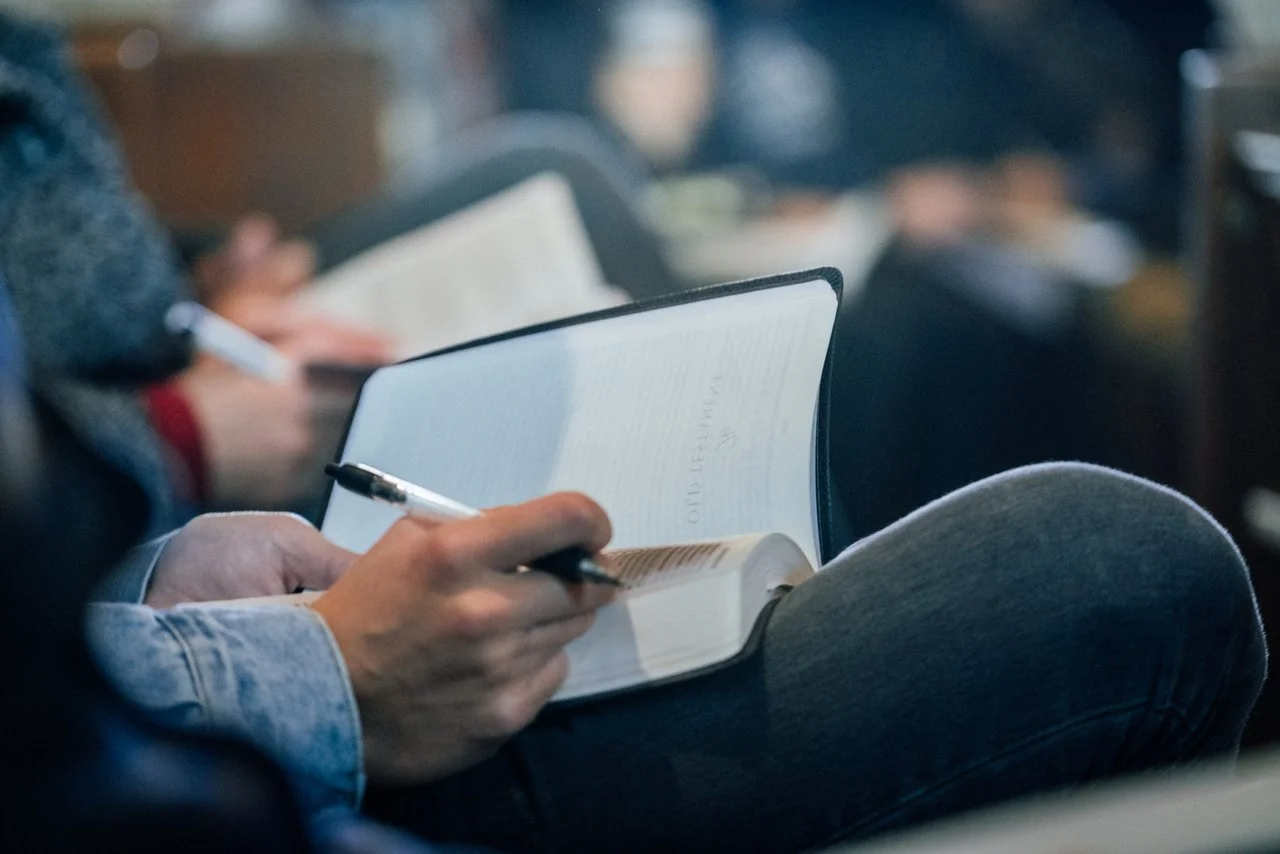 Announcement inviting you to read the Bible with us. Image is of an open Bible on a congregant's lap during church.