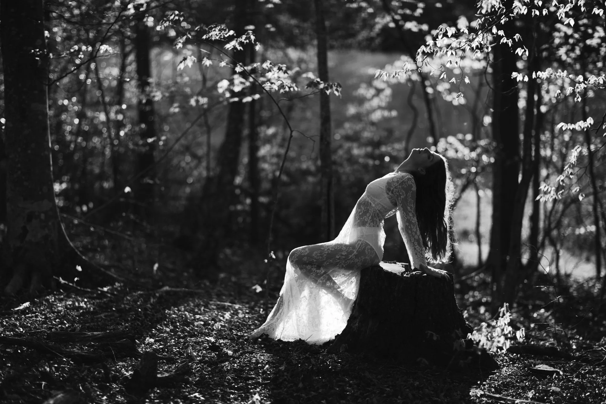 Black and white outdoor boudoir portrait of a woman wearing a white lacy gown in the woods of Charlottesville, Virginia.