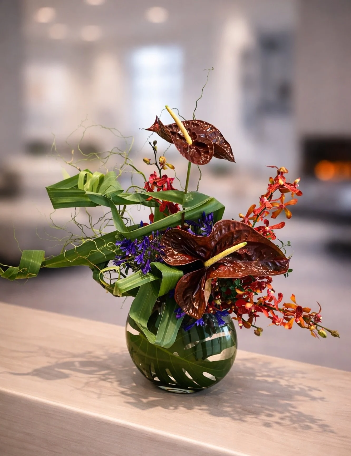Anthurium, orchid, and sculptural greens arranged with movement