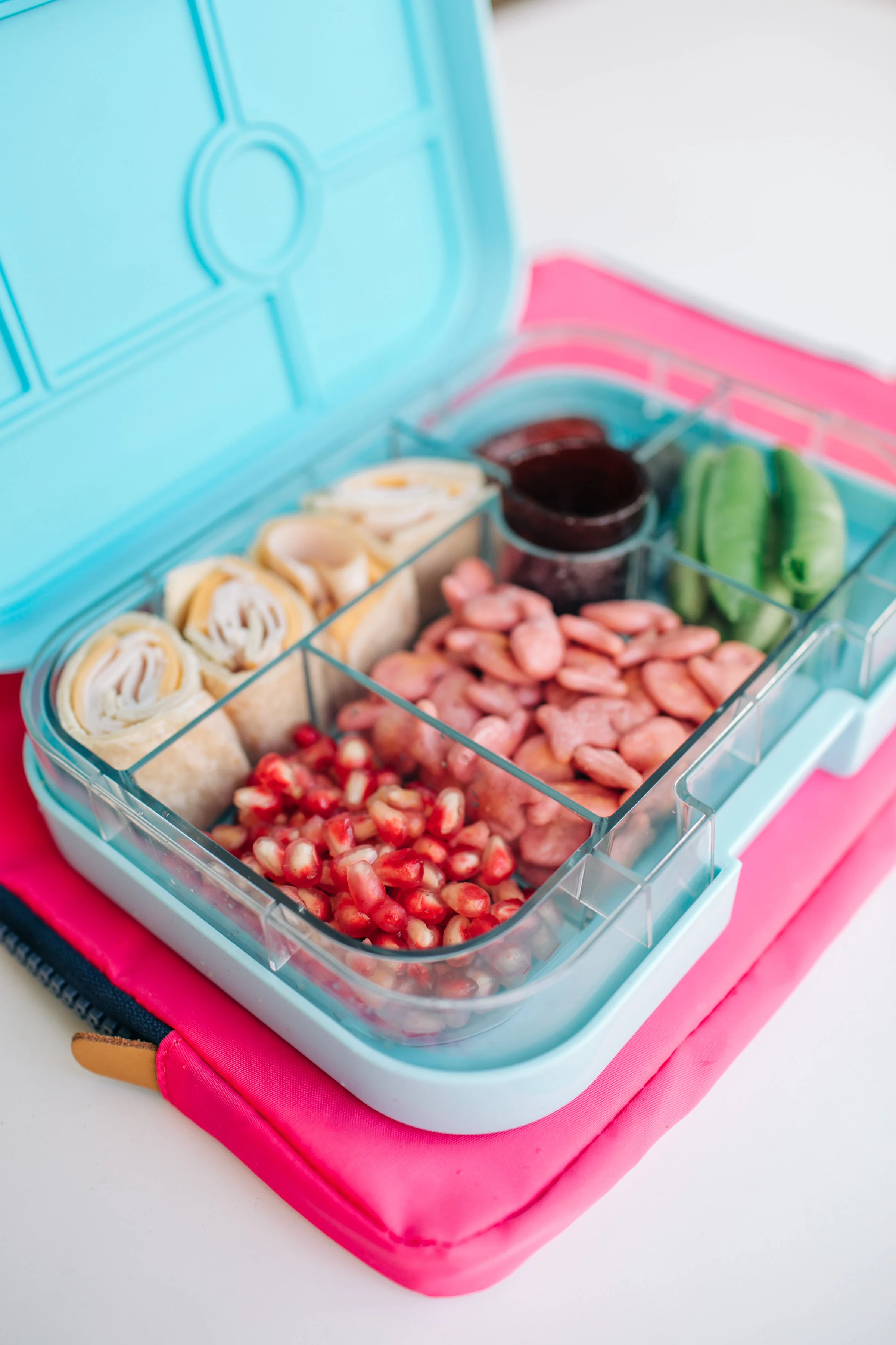 Turkey and Cheddar Tortilla Roll, Sugar Snap Peas, Fruit Leather, Goldfish Crackers, Pomegranate Seeds and two pitted Dates! This Yumbox here is the Original size.