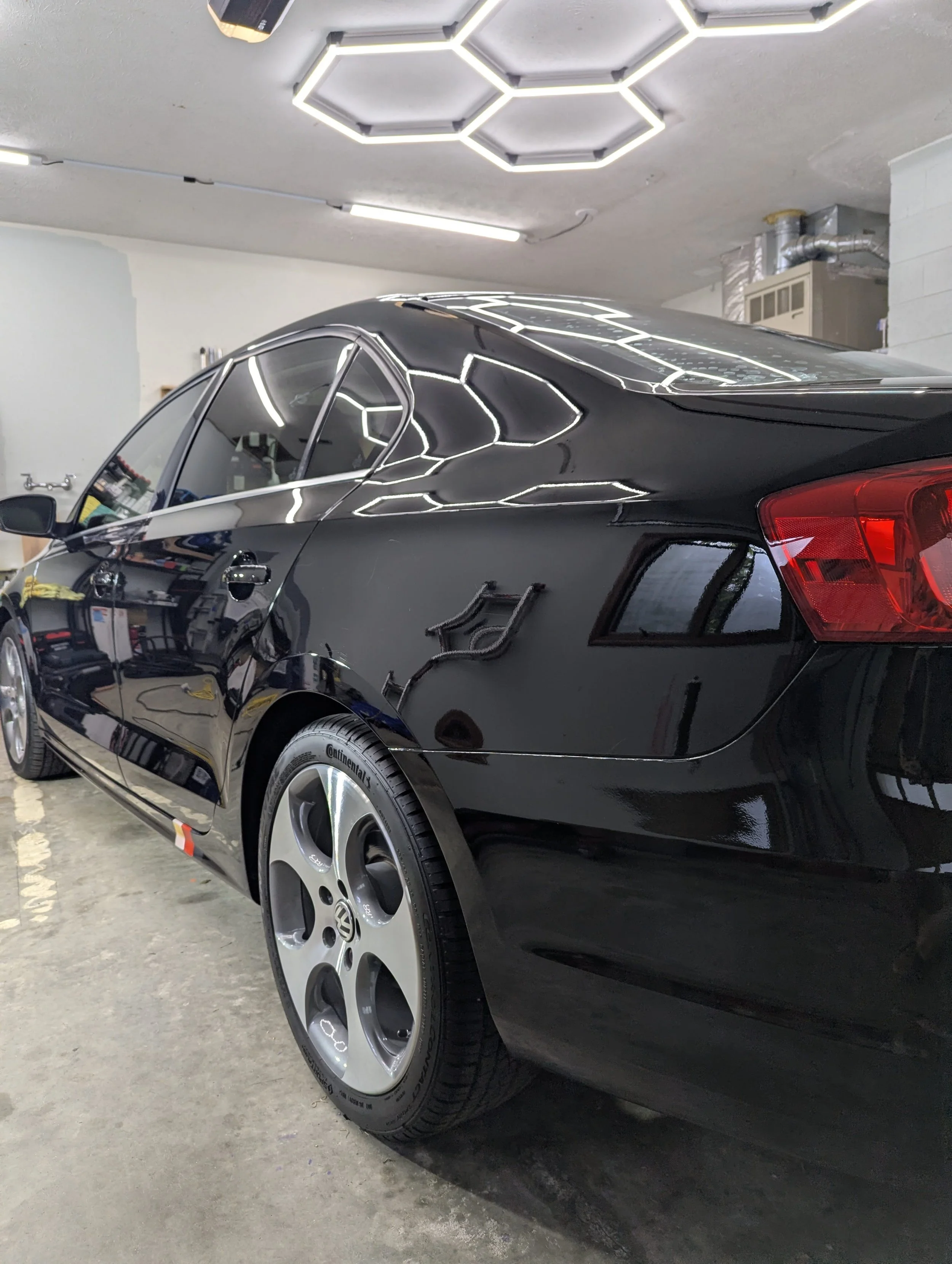 Black VW under the lights after two-step correction and coated with AMMO Reflex Pro