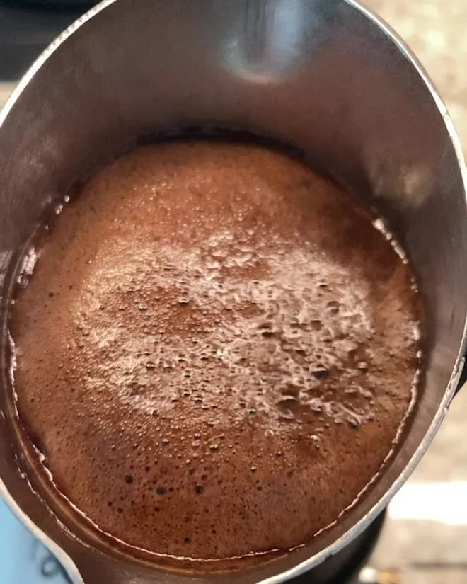 Armenian coffee foam rising in a jezve over a low flame