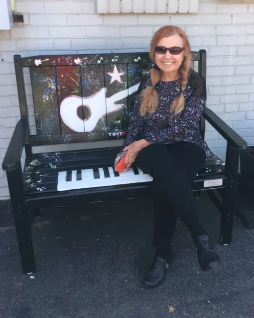 Rosemary on a bench she painted, currently on view in front of Tint-FX in Vienna, Va.
