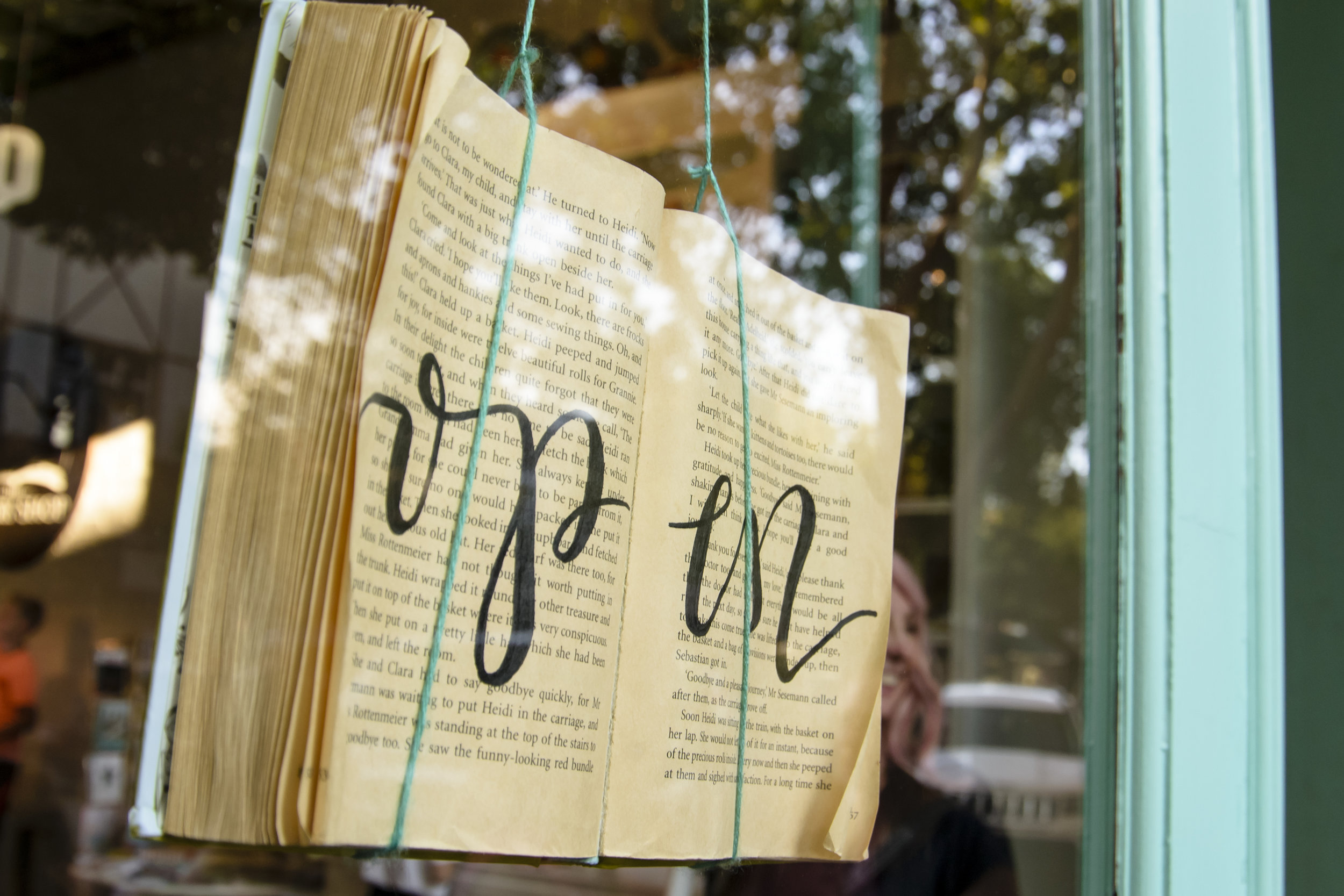 Open book display in the front window of The Story Shop children's bookstore, inviting families to visit in historic downtown Monroe, Georgia.