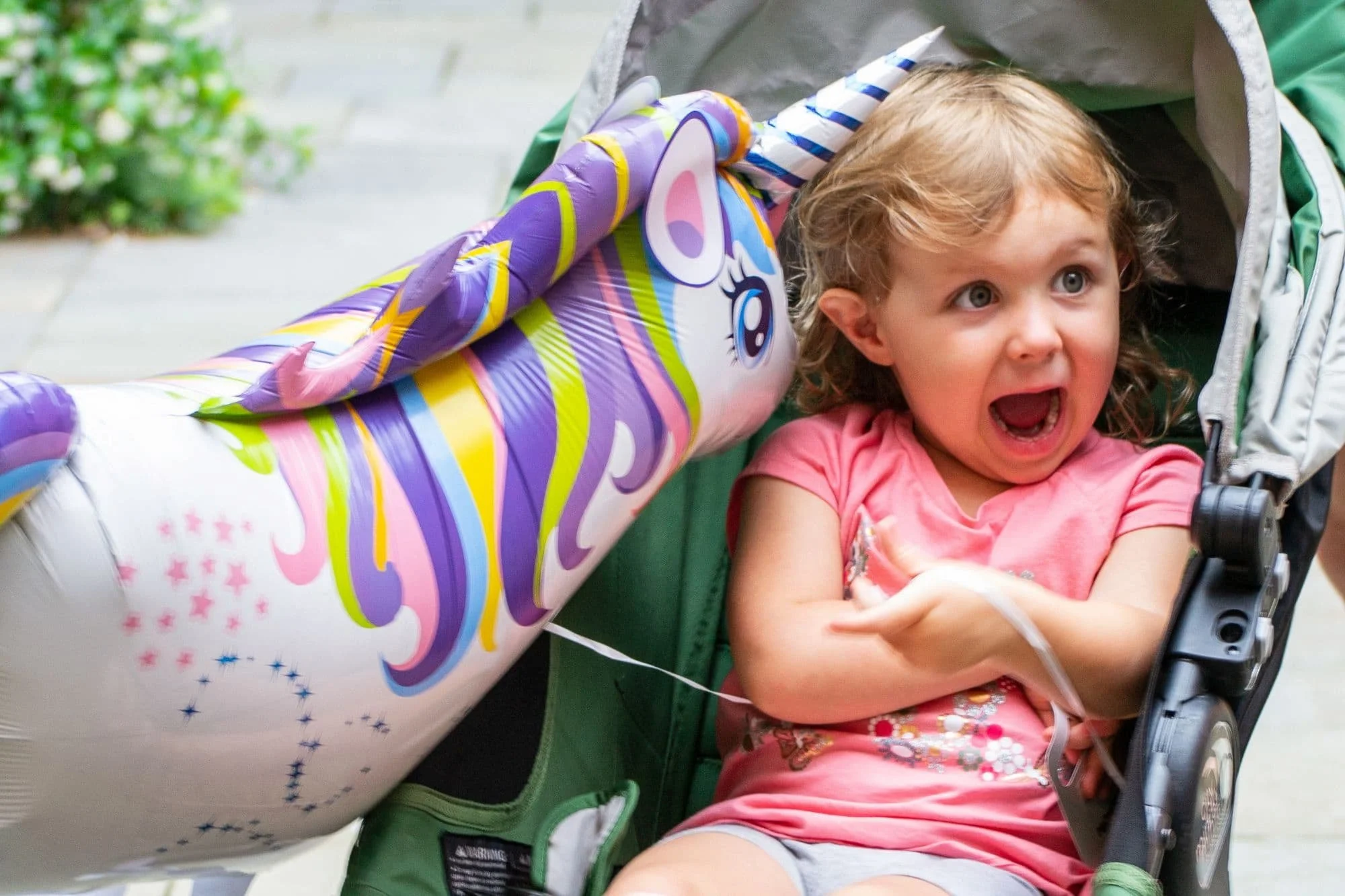 Young child reacts with excitement beside a giant unicorn balloon during Unicorn Day at The Story Shop children's bookstore in Downtown Monroe, Georgia.