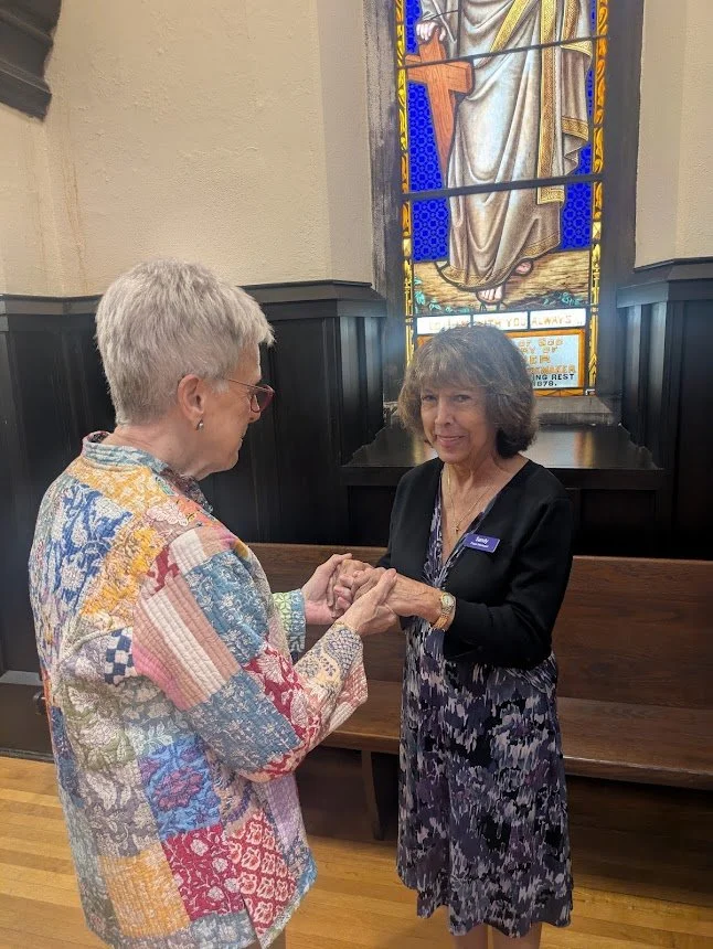 Prayer Intercessors holding hands in shared prayer before a stained glass window at Christ Church Glendale, Ohio.