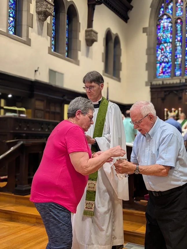 A lay chalice bearer offers the communion chalice alongside clergy during Sunday Holy Eucharist at Christ Church Glendale.