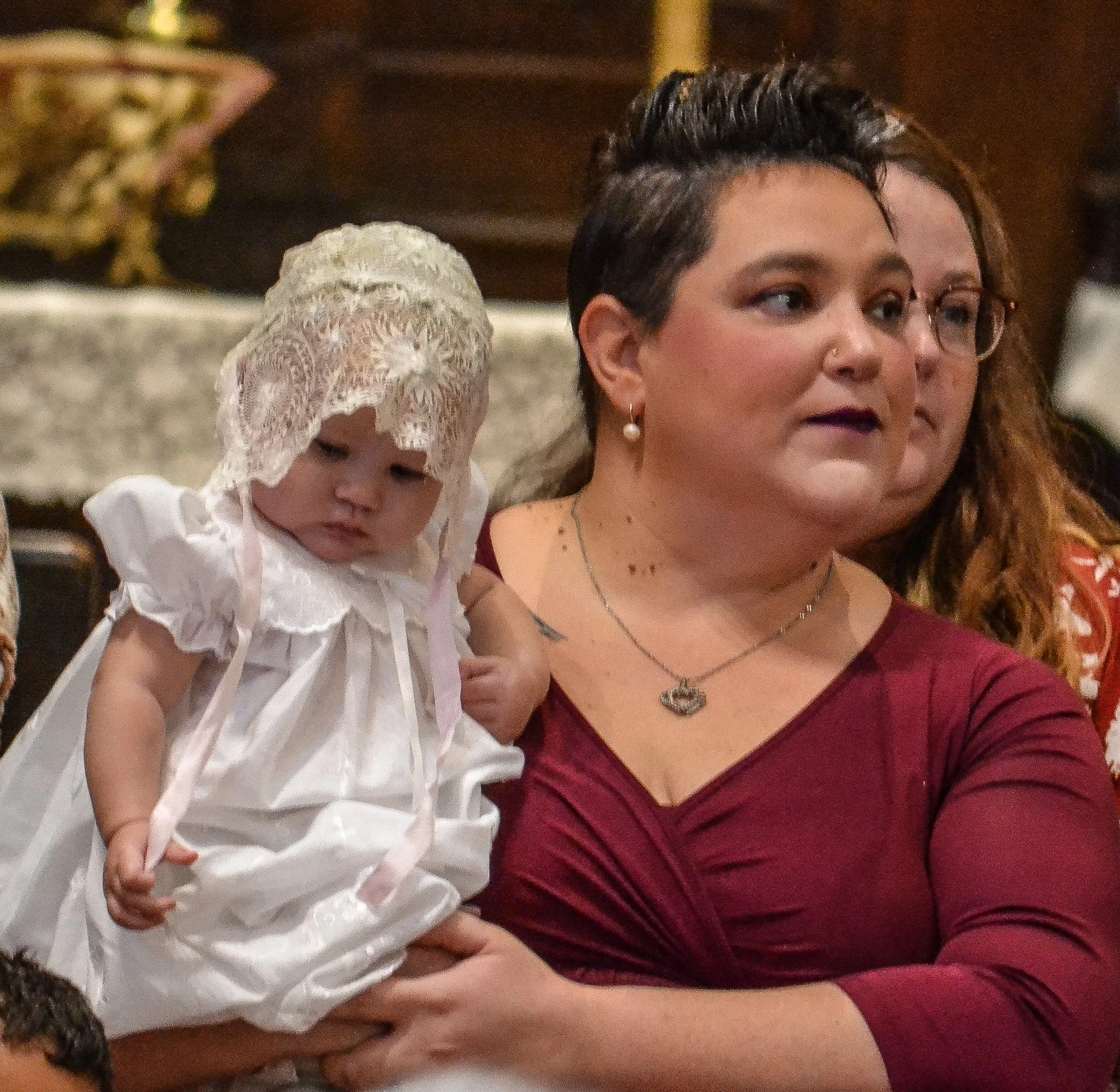 A mother and her infant stand at the alter for a baptism.