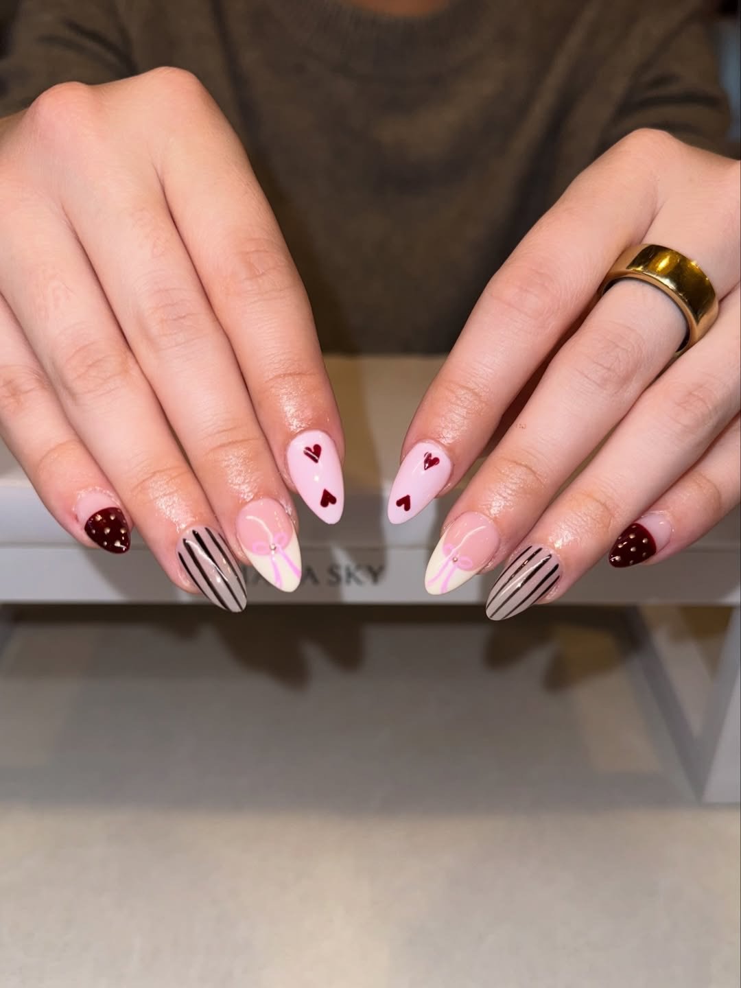 Soft pinks, tiny hearts, bows, and subtle stripes come together for a set that feels light, polished, and a little romantic.

Perfect for everyday wear, but still special enough to stand out.
Book your custom nail art set today and let us create some
