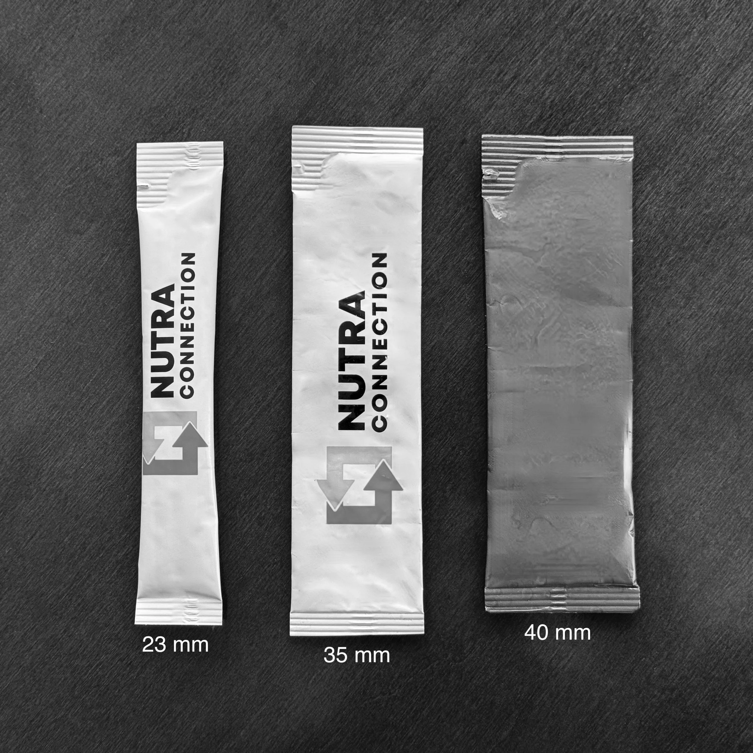 Black and white photo of three stick packs side by side on a desk. From left to right, the stick packs shown have widths of 23 mm, 35 mm, and 40 mm.