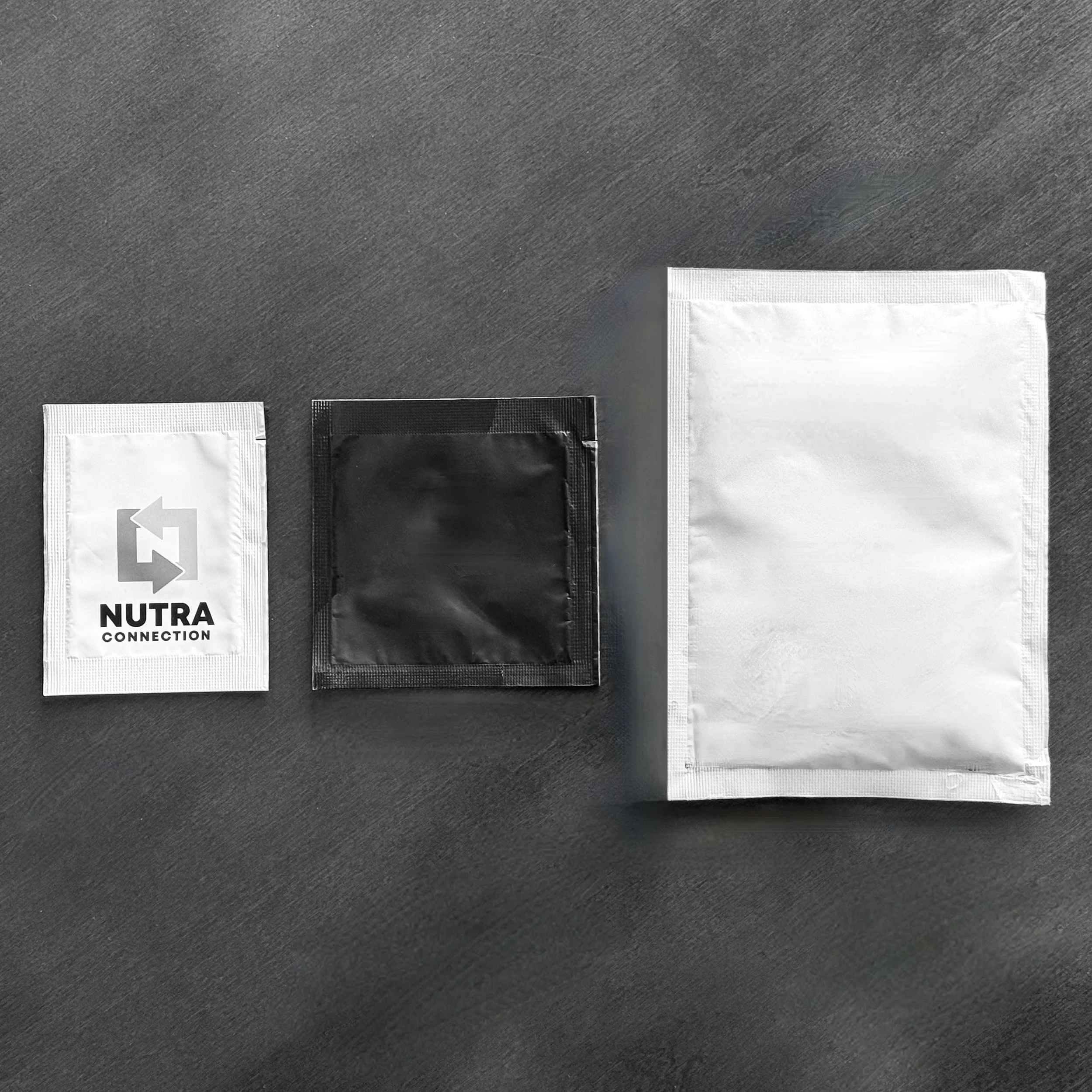Three sachets side by side on a dark background. Each are different widths and the one on the left has Nutra Connection's logo on it.