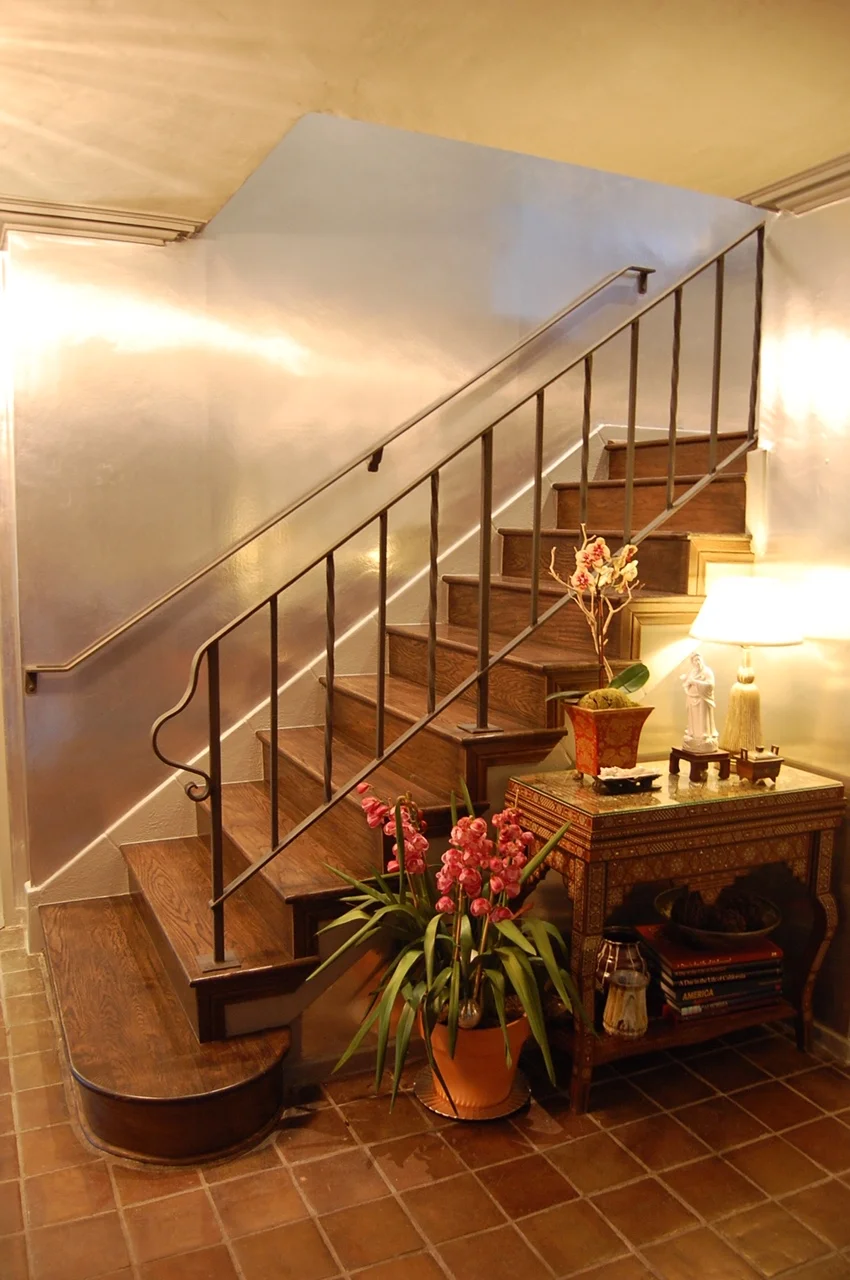  BEVERLY HILLS RESIDENCE  Harmonized an eclectic Mediterranean foyer by installing walnut stained oak stairs, adding a raw iron finish to the handrail and staining the original Saltillo tile warmed the silver leaf wallcovering. 