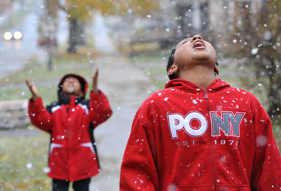  Kyle Peters, 10, right, and Izzy Peters, 8, try to catch snowflakes in their mouths and hands as the first snowflakes fall Thursday, Nov. 10, on Henry Street in Grand Rapids. 