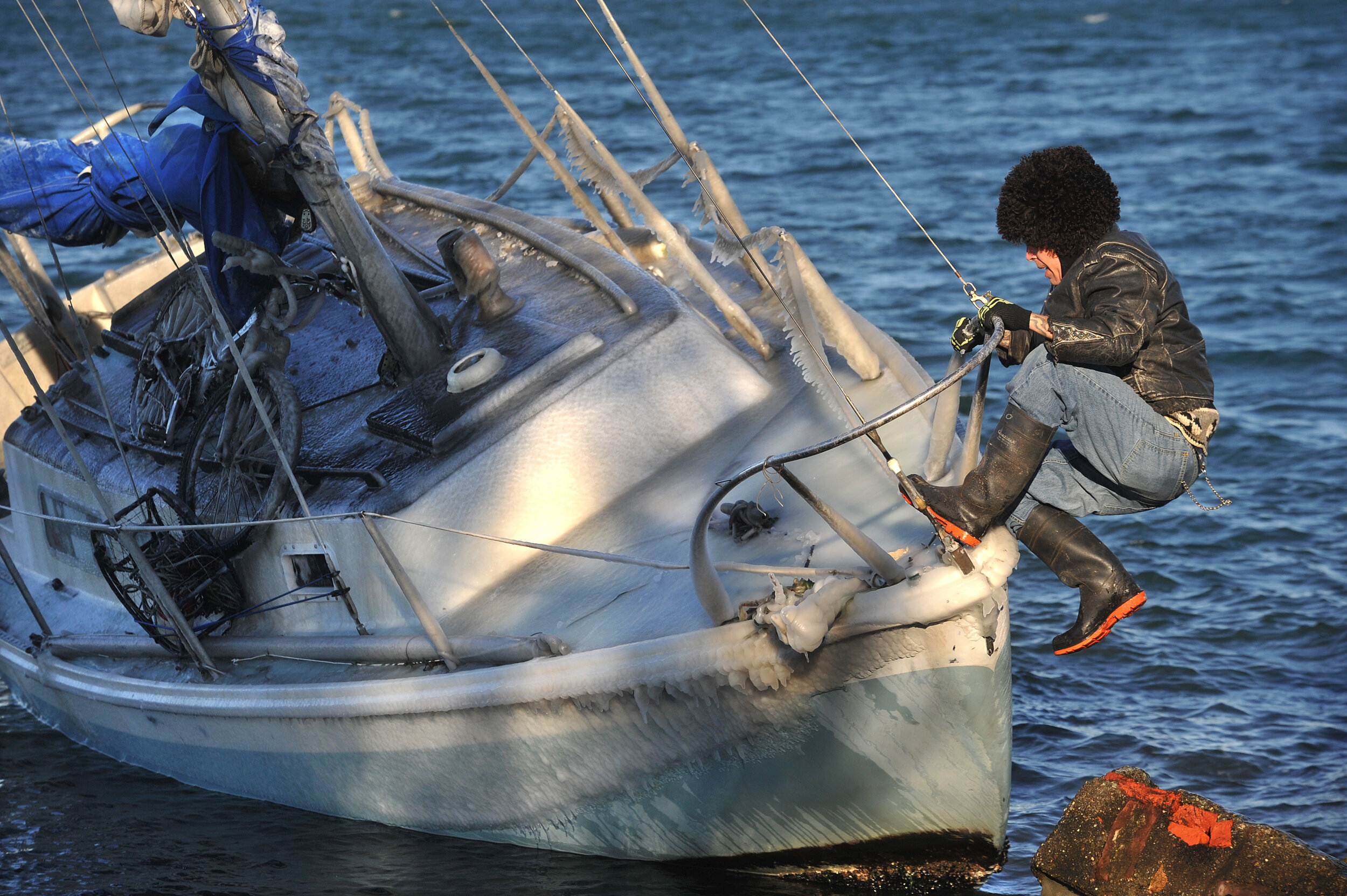  Owner Roger Coderre climbs on to the front of his boat Tuesday morning, Nov. 23, after he learned it came ashore due to high winds the previous night. Coderre said there was no damage to the boat and wasn't taking on water so he tied it to a nearby 