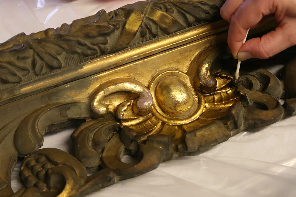 Conservation and restoration often means trying to fix previous incompetent and inappropriate repairs. These are often much more difficult to repair than the original repairs would have been due to the introduction of incompatible coatings or adhesives that are very difficult to separate and remove from the original material. Sometimes you get lucky as we did recently with a gilded frame for a local client. The carved wood frame came in completely covered with a bronze powder coating that seemed fairly recent though badly oxidized and was a dark green/brown. It was obvious that there were some losses of gesso on two of the corners but the rest of the carving seemed to be intact. Testing showed that the binder of the coating was nitrous- cellulose lacquer that broke down quickly with the introduction of lacquer thinner. Read full story...