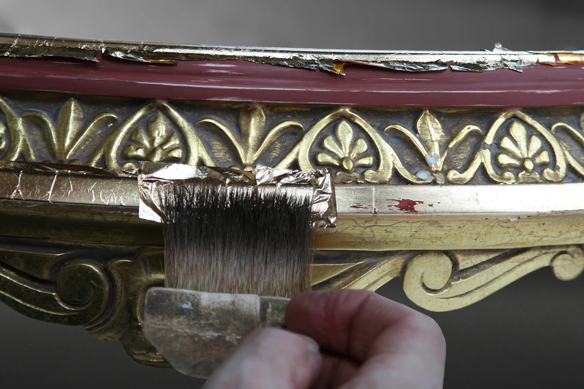 Gold leaf is gently applied to areas of gilding loss