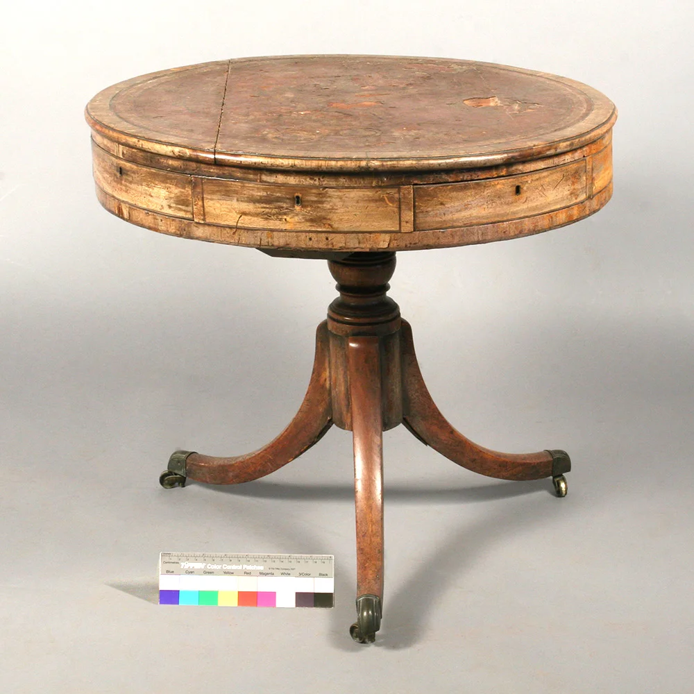 Drum table with with visible damage related to structure, leather top, and finish