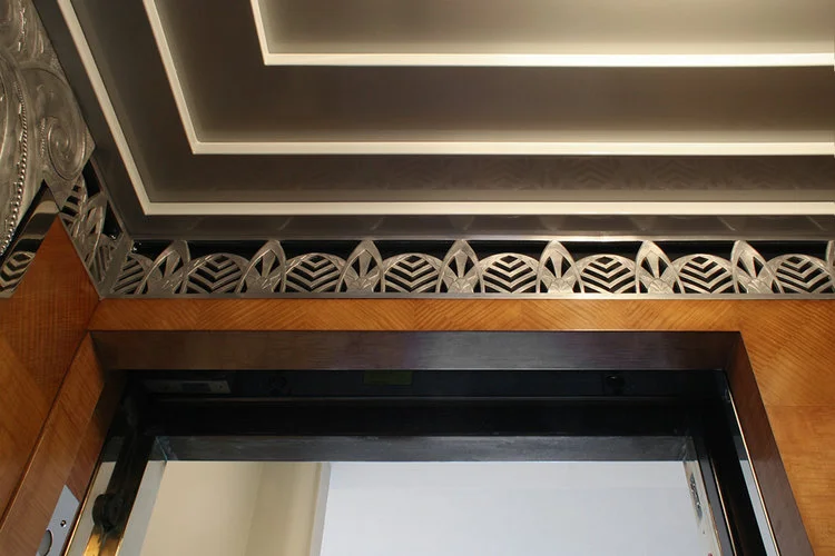 Elevator cab interior after restoration; detail of repaired veneer above the door