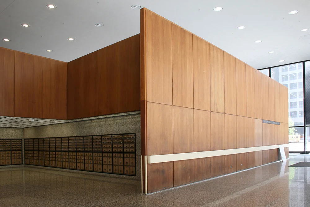 Detail of the West wall panel section showing excessive water damage staining and dirt along the bottom. There is also unoriginal protection rail and white corner guards installed years after the building was completed. | Photo courtesy of GSA