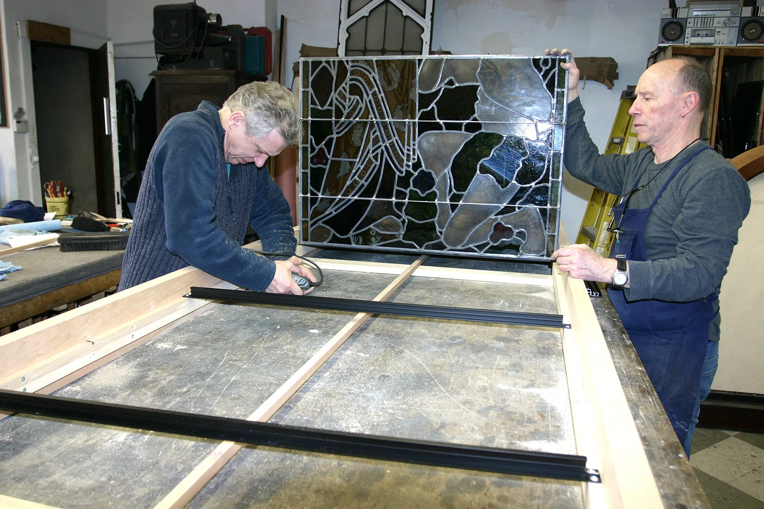 Making size adjustments to the frame to fit stained glass panels properly before finish is applied to the frame.