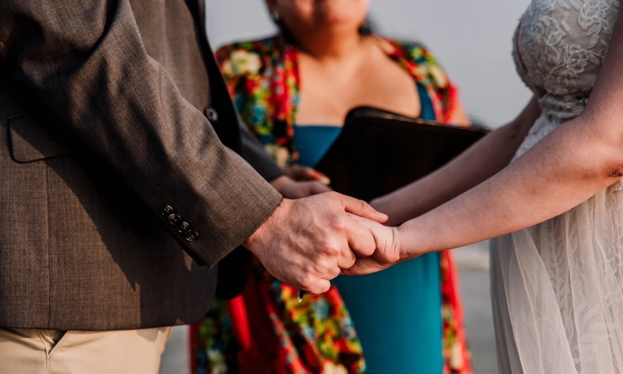 “Two people holding hands during a beach wedding ceremony in Port Aransas, Texas, officiated by Renee Reyes.”