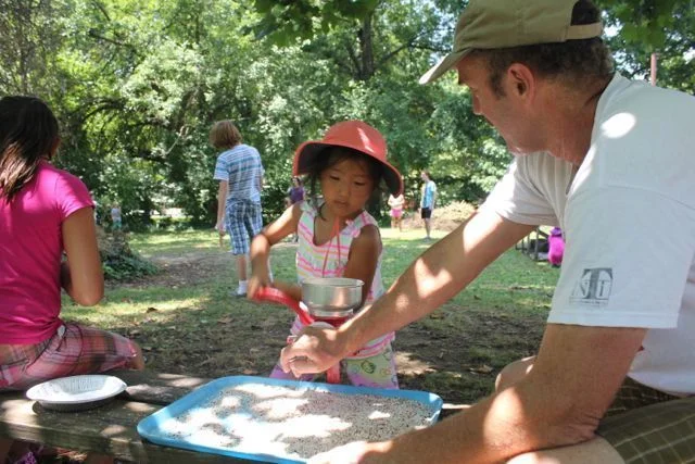 Future farmer grinding corn at Sustainable Agriculture of Louisville Garden Camp