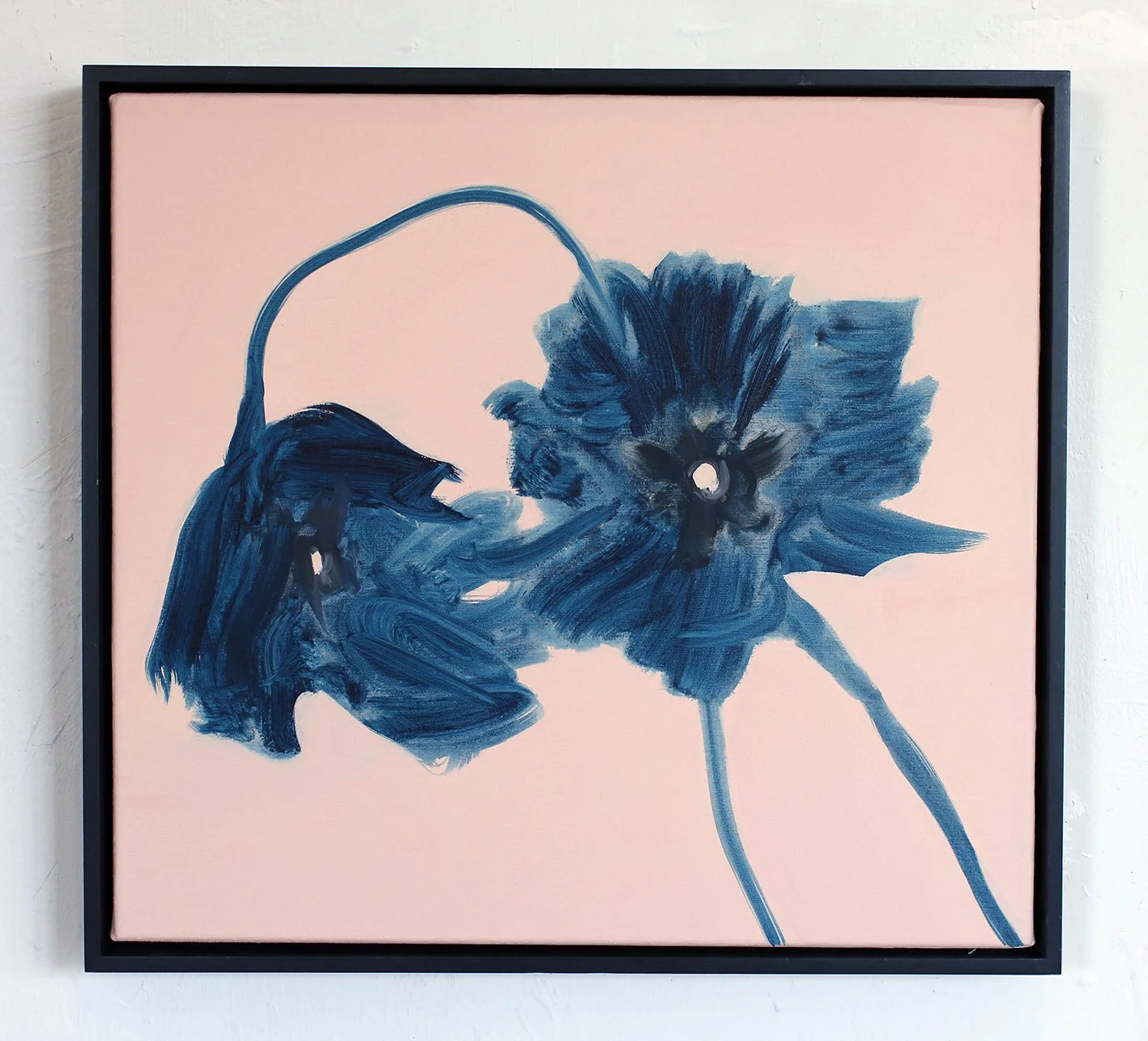 Abstract painting of blue flowers on a pink background, with dark blue and white accents, framed and hung on a wall.