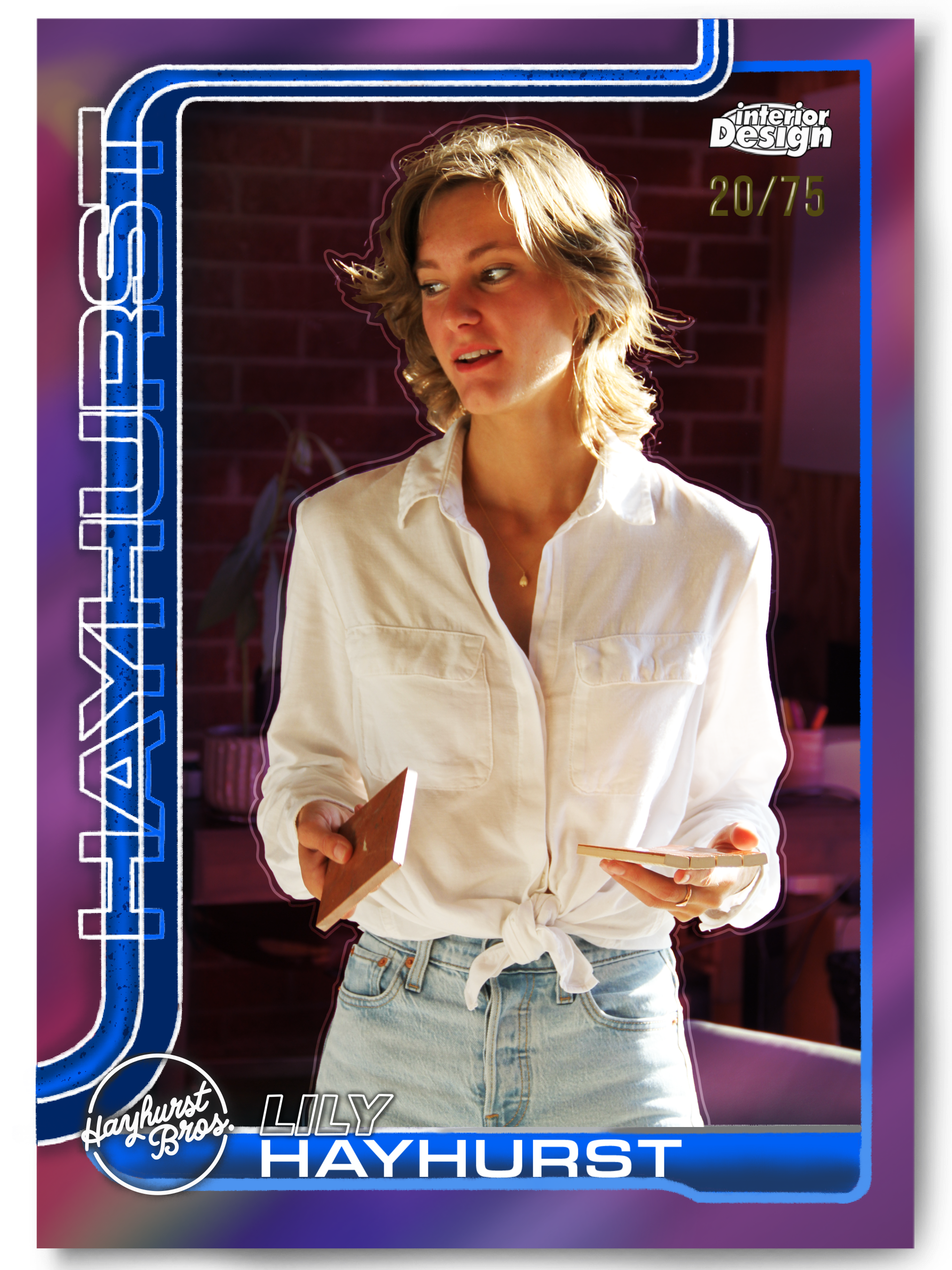 A woman with blonde hair wearing a white shirt and jeans, standing indoors with a brick wall background, holding a paint swatch and a sample board, in front of a colorful graphic design poster.