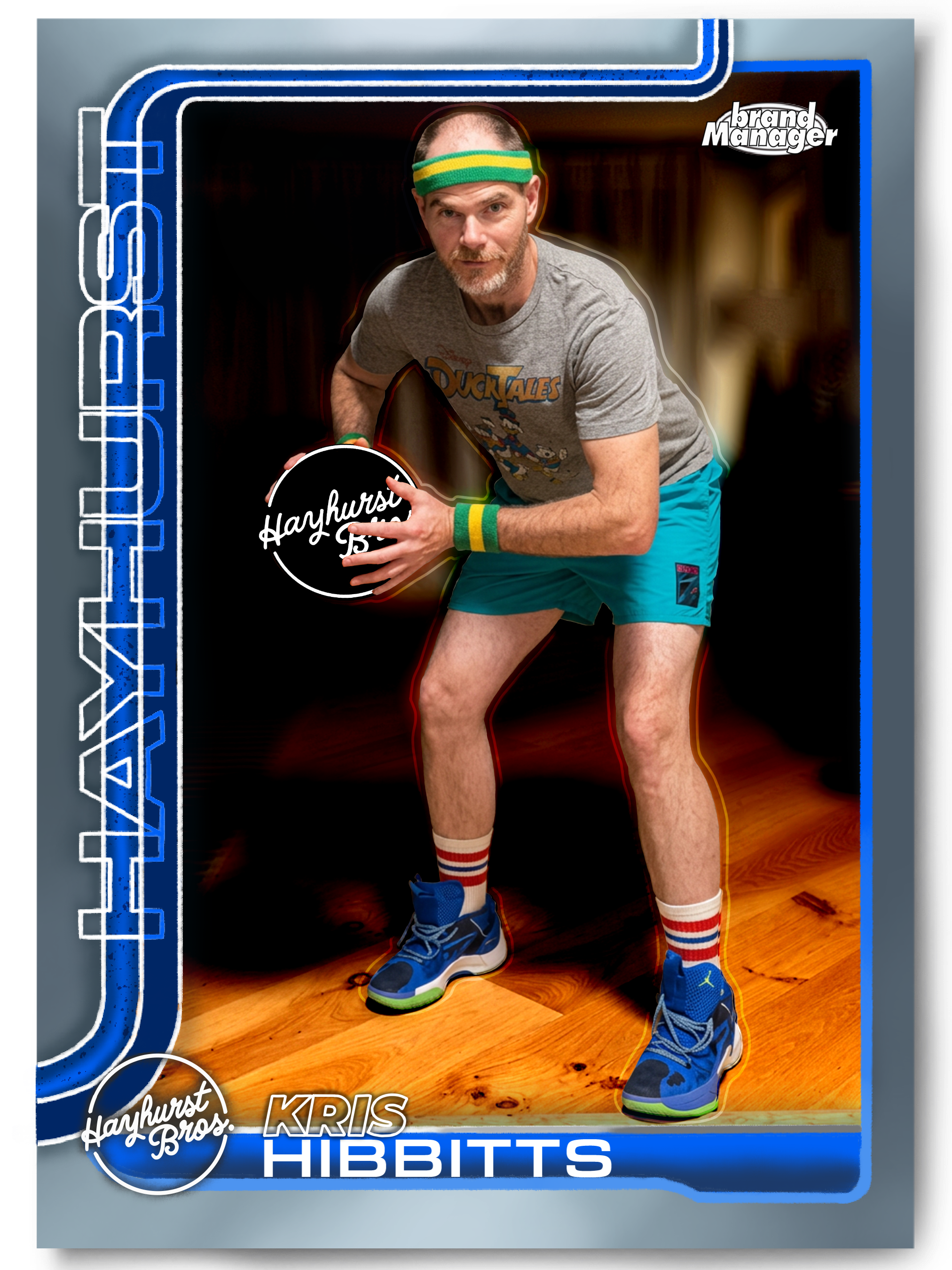 Action figure of Kris Hibbitts from the Hayhurst Bros. series in a sports pose, wearing a gray T-shirt with Disney's DuckTales logo, teal shorts, colorful striped socks, and blue sneakers, in a box with a blue and black design.