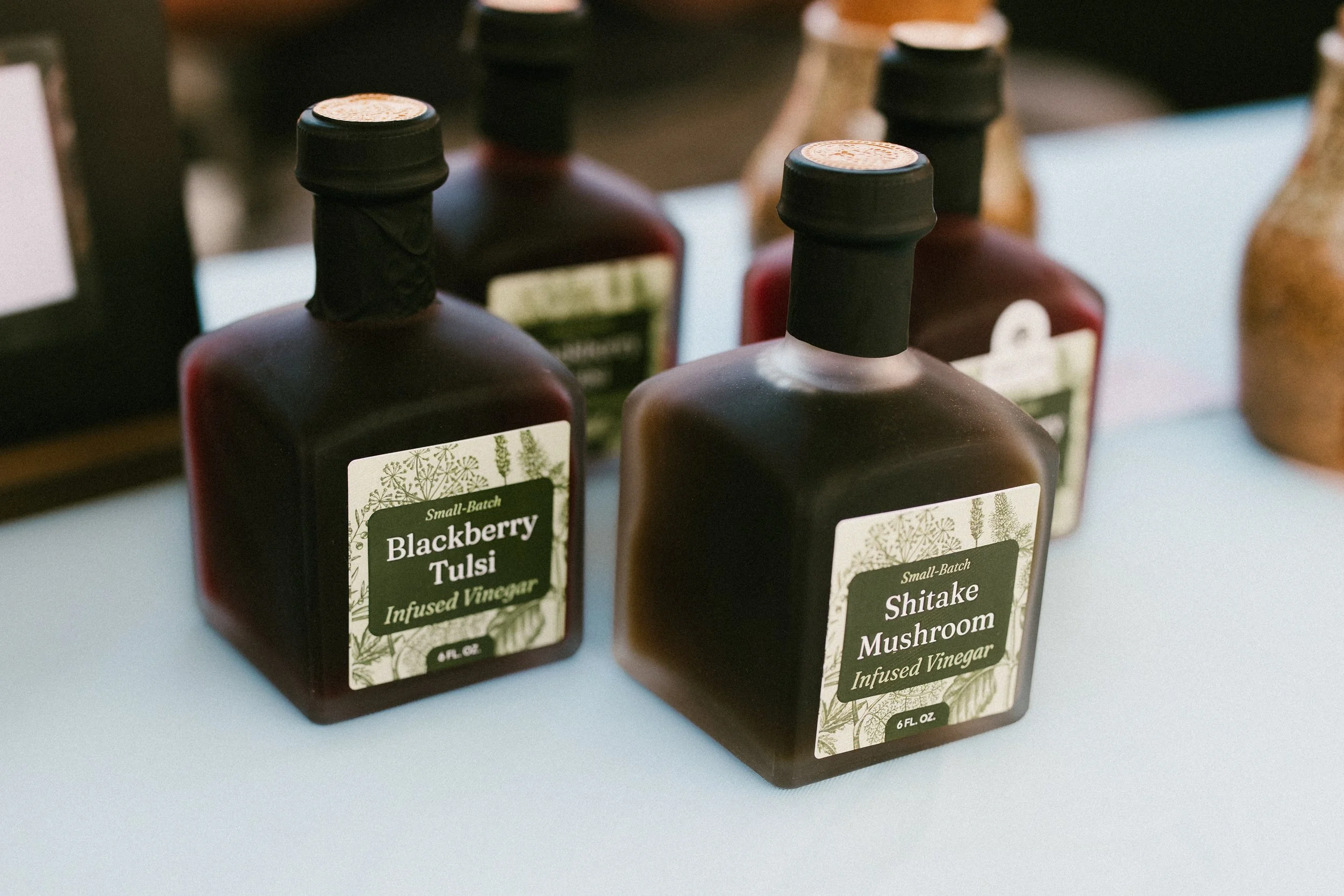 A small jar of honey labeled "Tulsi Honey," a jar of a yellow powder, and a crystal mounted on a pin, all placed on a crocheted lace surface.