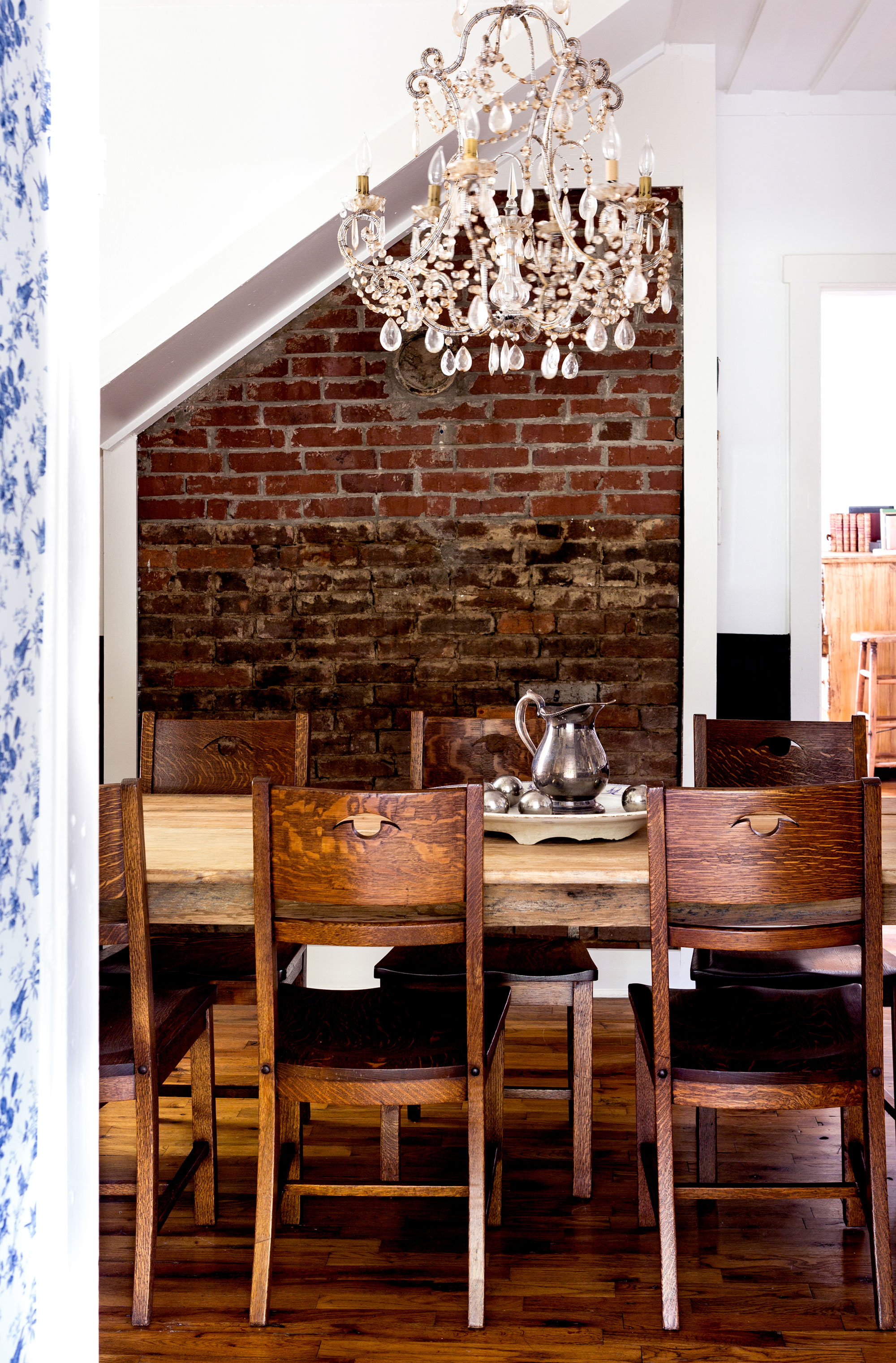 With Holly’s found heirlooms on the walls, black beadboard paneling on white walls, a crystal chandelier, and a large farm table that easily seats eight, the cottage’s dining room is relaxed enough for family cookouts and regal enough for Sunday dinners.