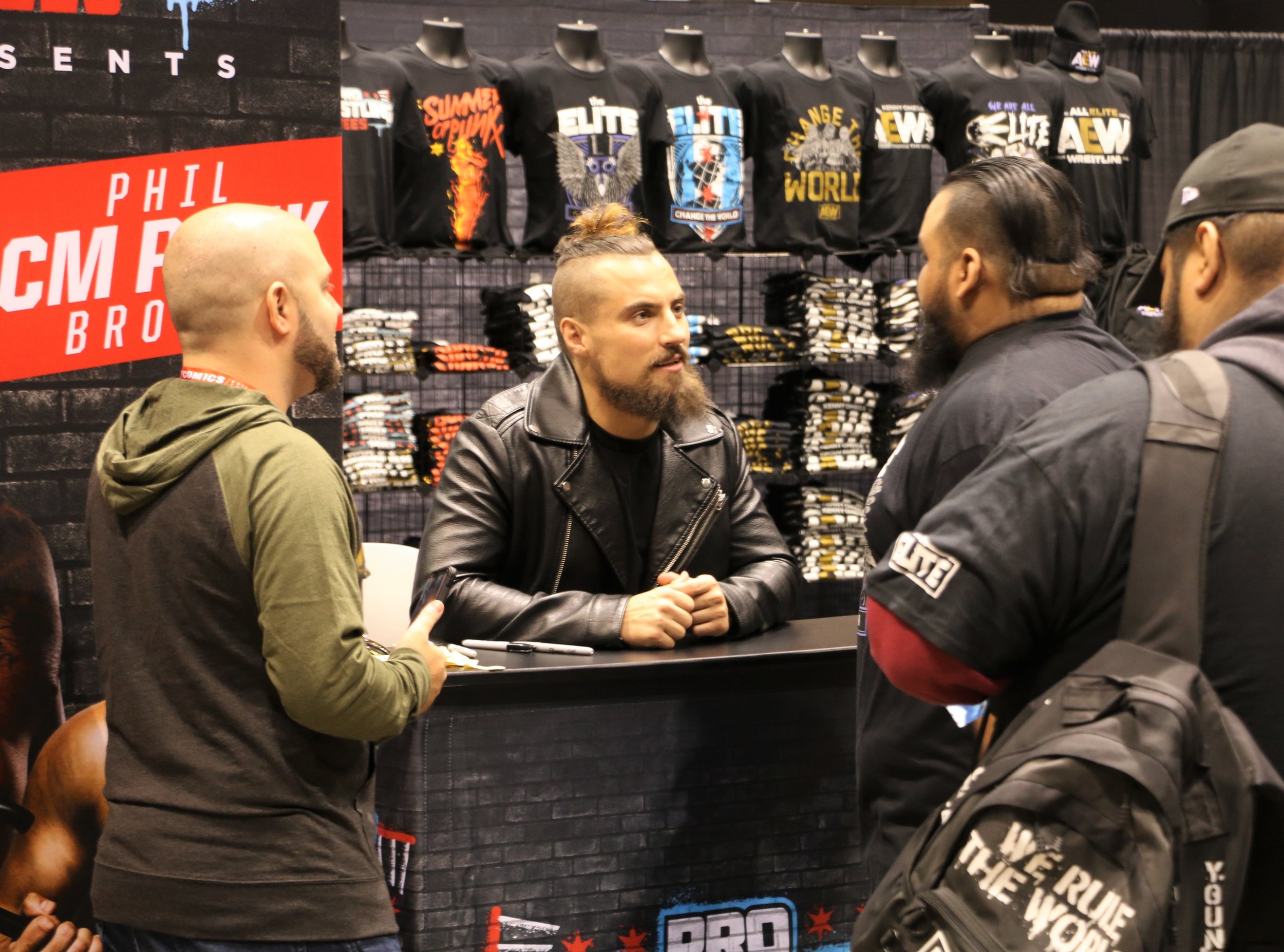  Ring of Honor star Marty Scurll, center, talks with fans at the Pro Wrestling Tees booth. 