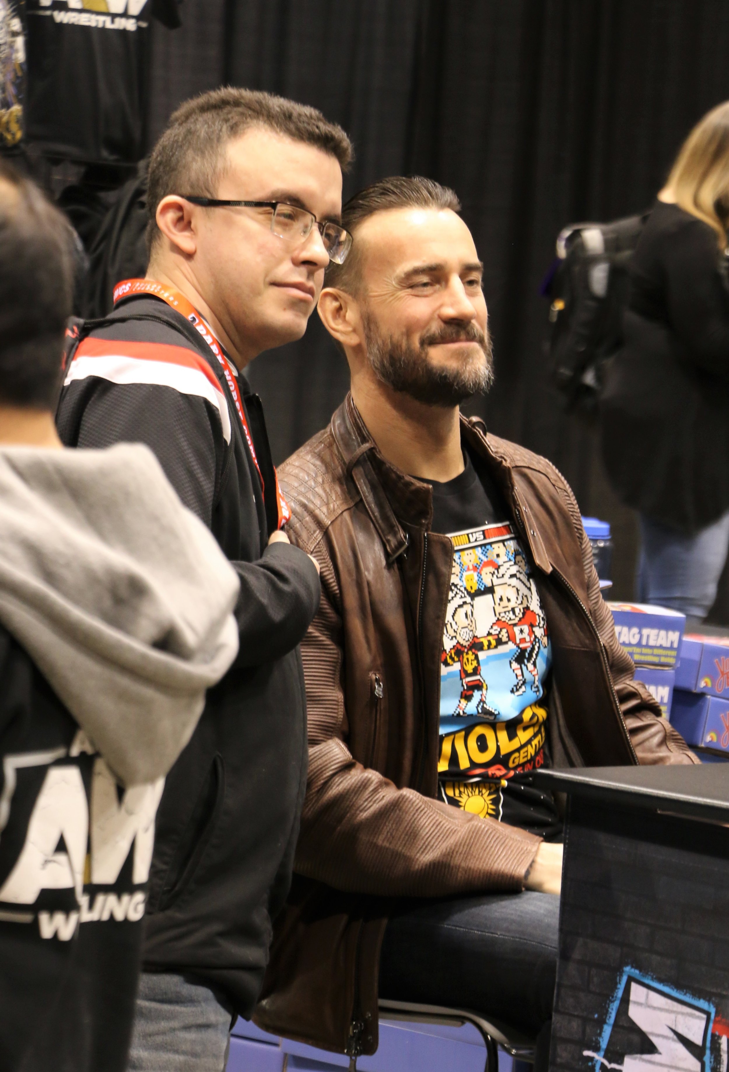  CM Punk, right, poses with a fan at the Pro Wrestling Tees booth. 