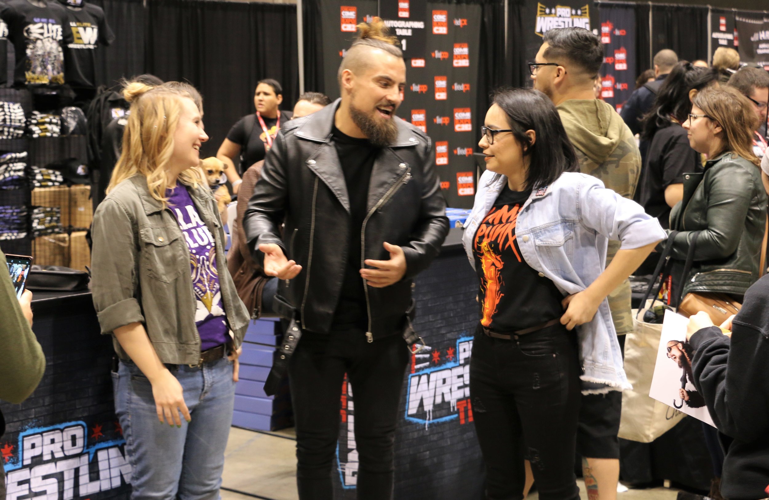  ROH star Marty Scurll, center, talks with fans at Pro Wrestling Tees booth. 