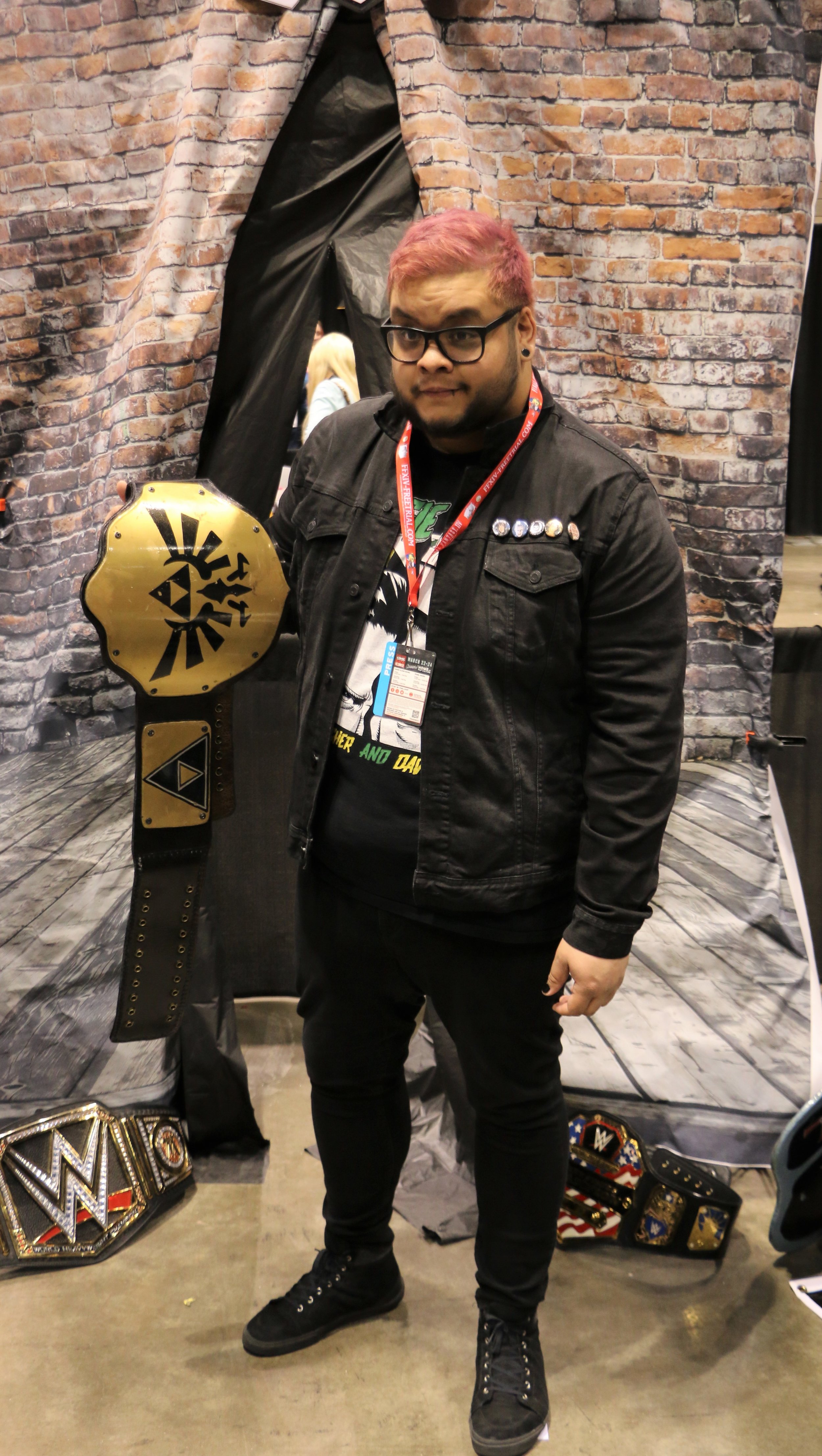  A fan poses with the “Triforce” championship belt at the Too Sweet Cosplay booth. 