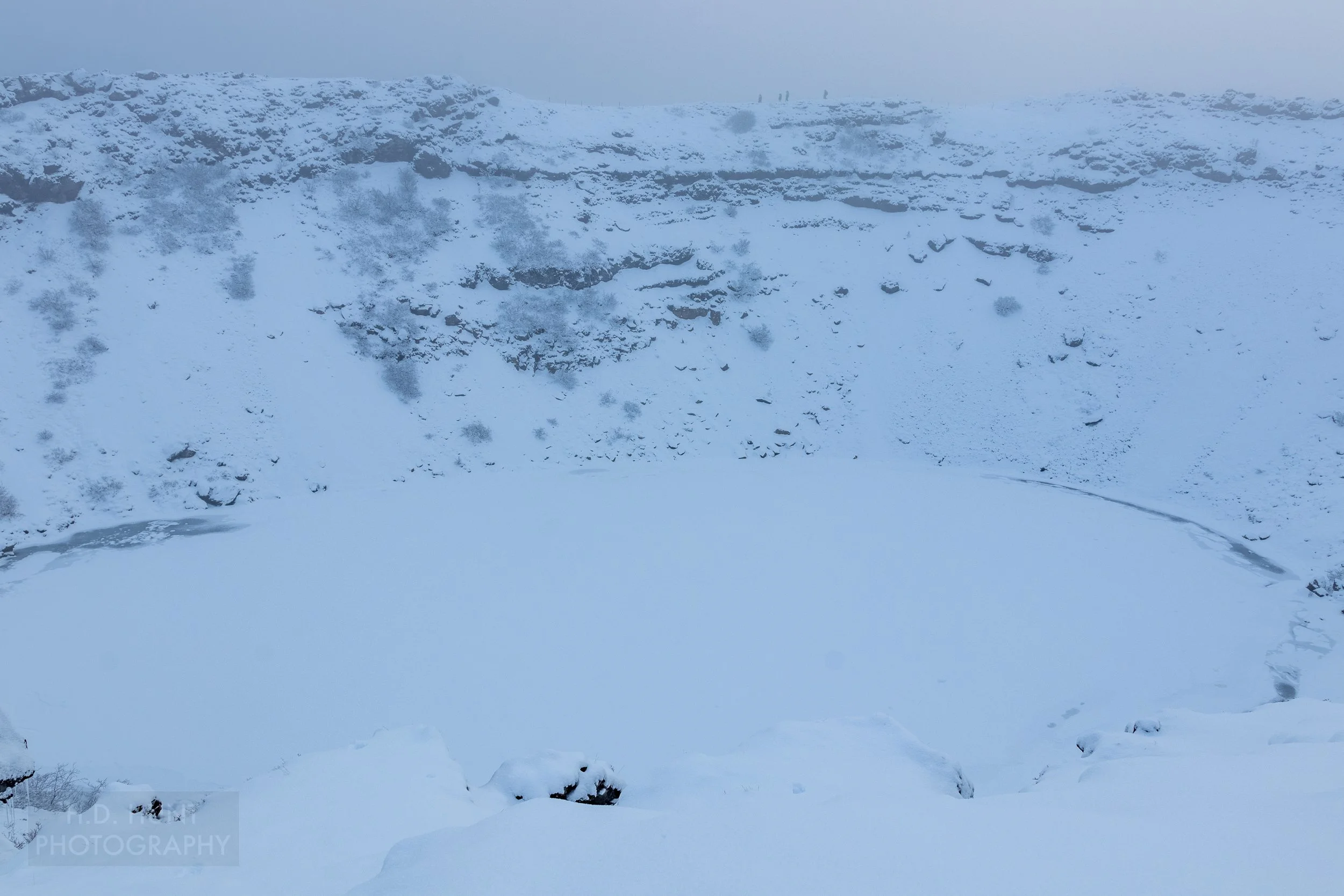 Snowed-over water sits in the bowl of Kerið Crater, Iceland.