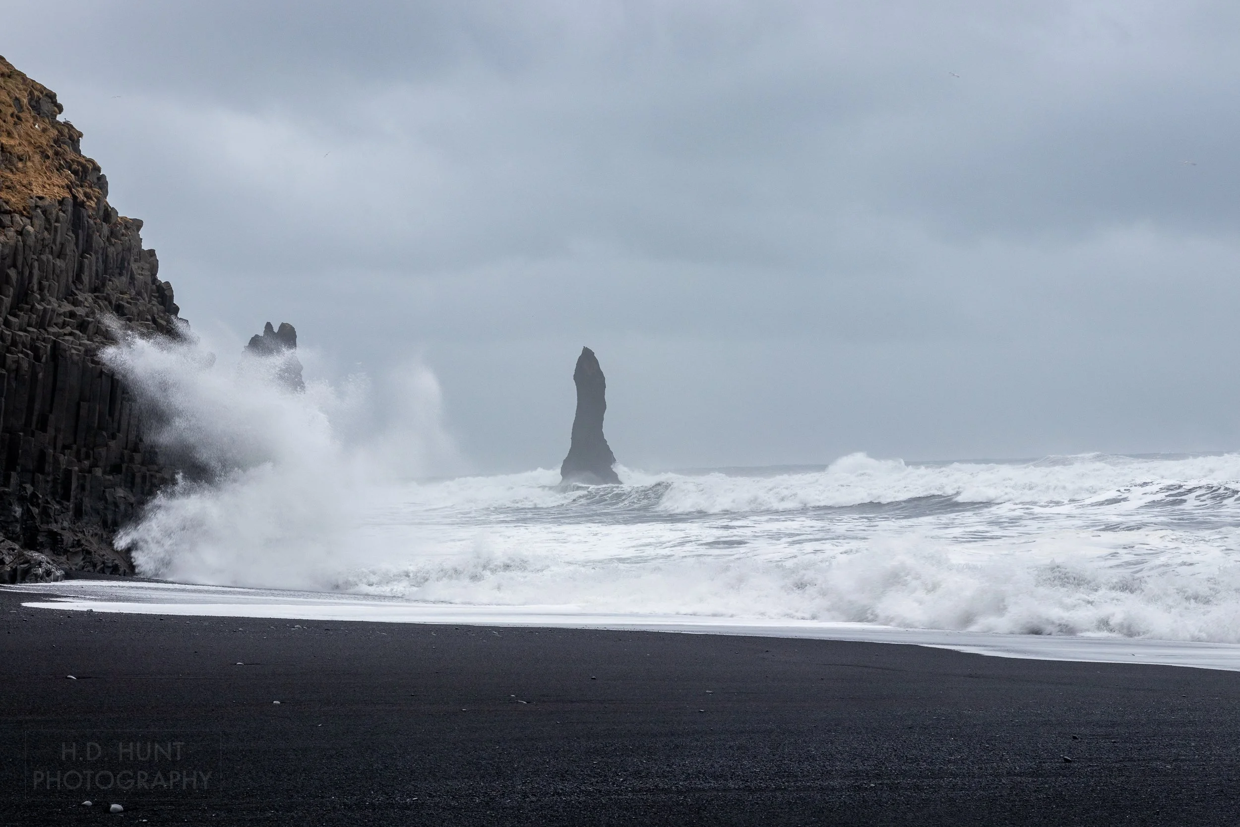 A large wave crashes against the cliffs at Reynisfjara, Iceland