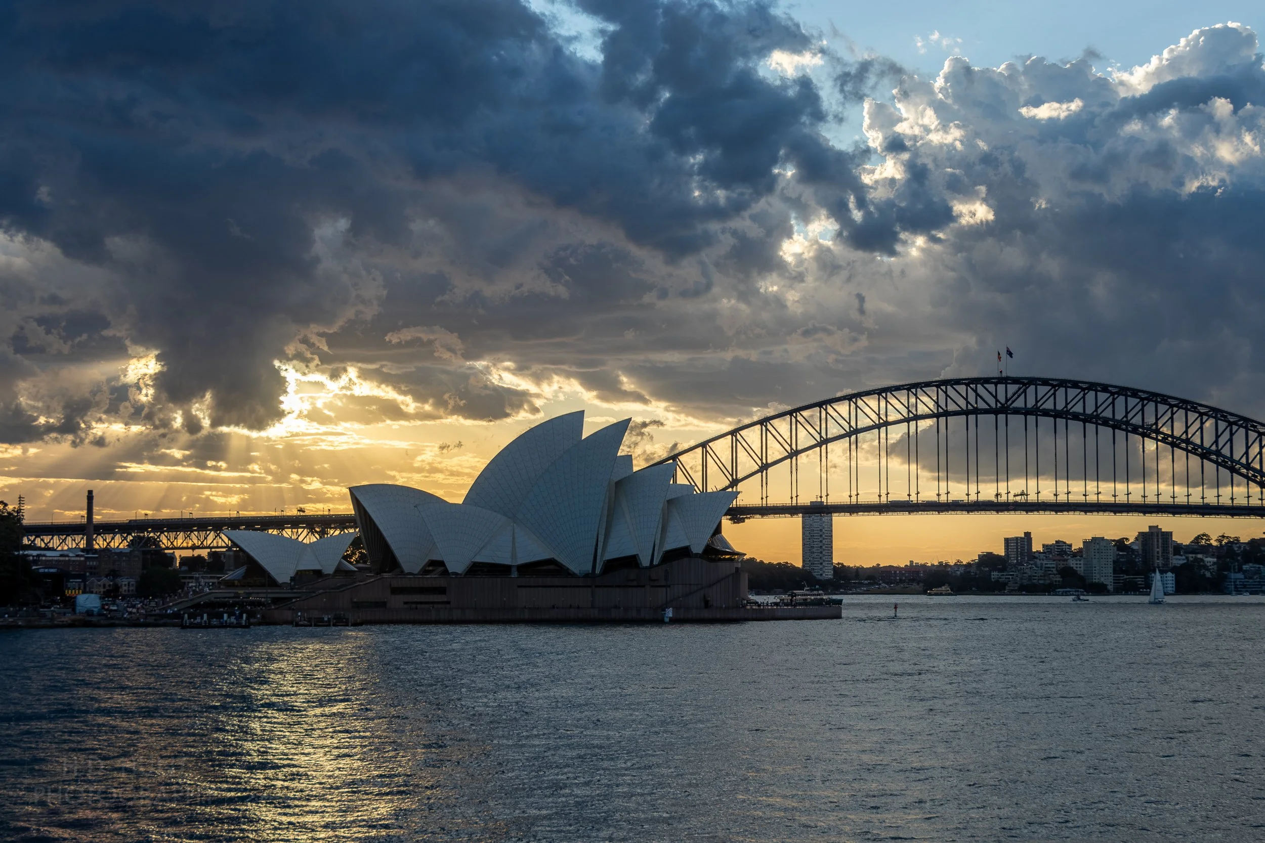 Sunlight peeks through clouds behind the Sydney Opera House, Sydney, Australia.