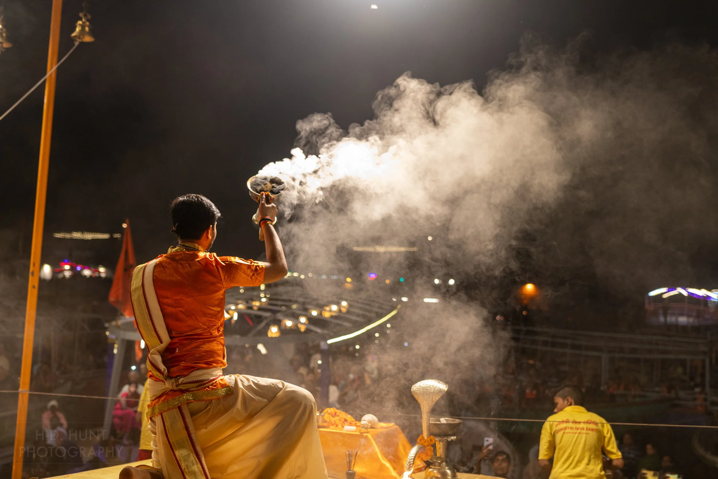 A man wearing a religious outfit creates smoke during a Hindu religious ceremony called arti, Varanasi, India.