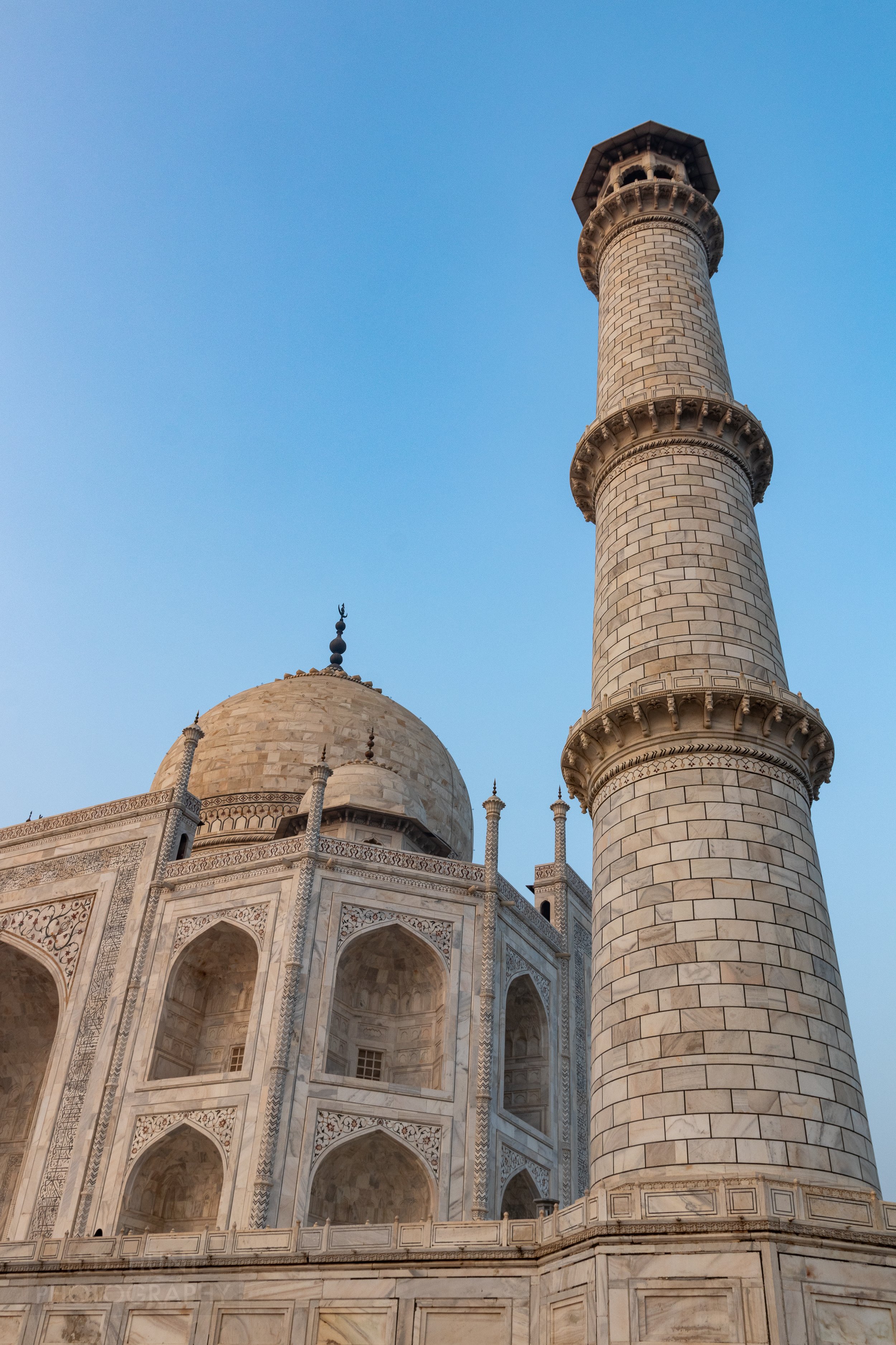 A minaret tower at the Taj Mahal is seen in the foreground of the main white marble mausoleum building, Agra, India.