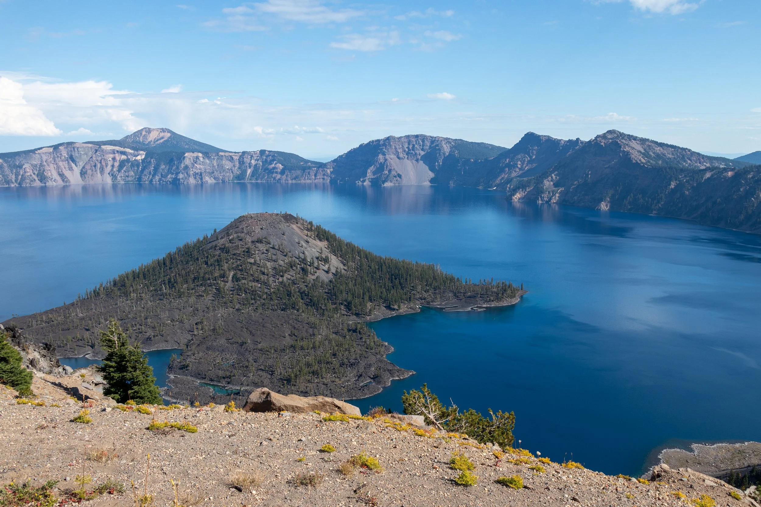 A view of Wizard Island surrounded by the blue waters of Crater Lake from Watchman Overlook, Crater Lake National Park, Oregon, United States.