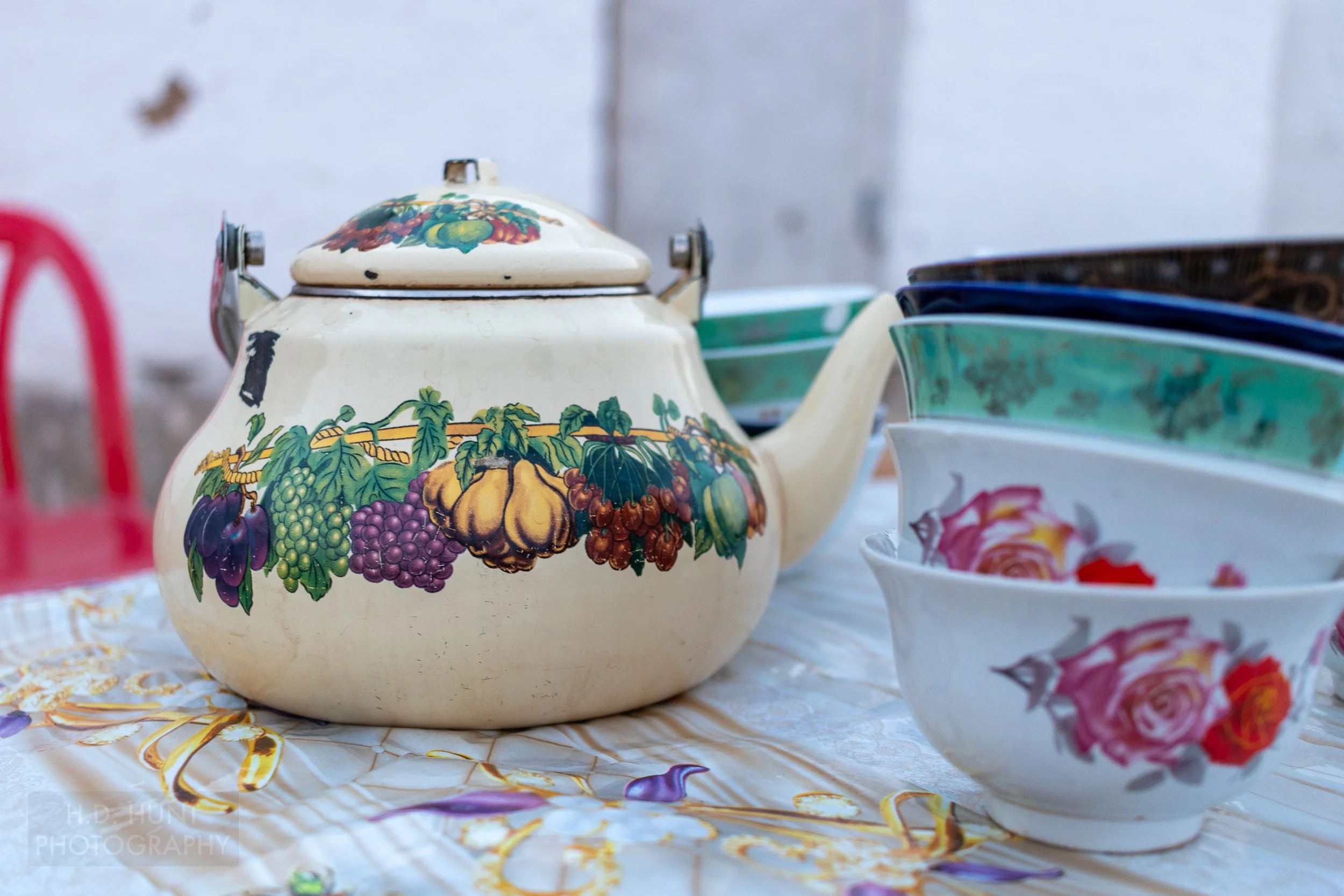 A colorful teapot featuring painted fruits sits on a table in Yangikazgan, Uzbekistan.