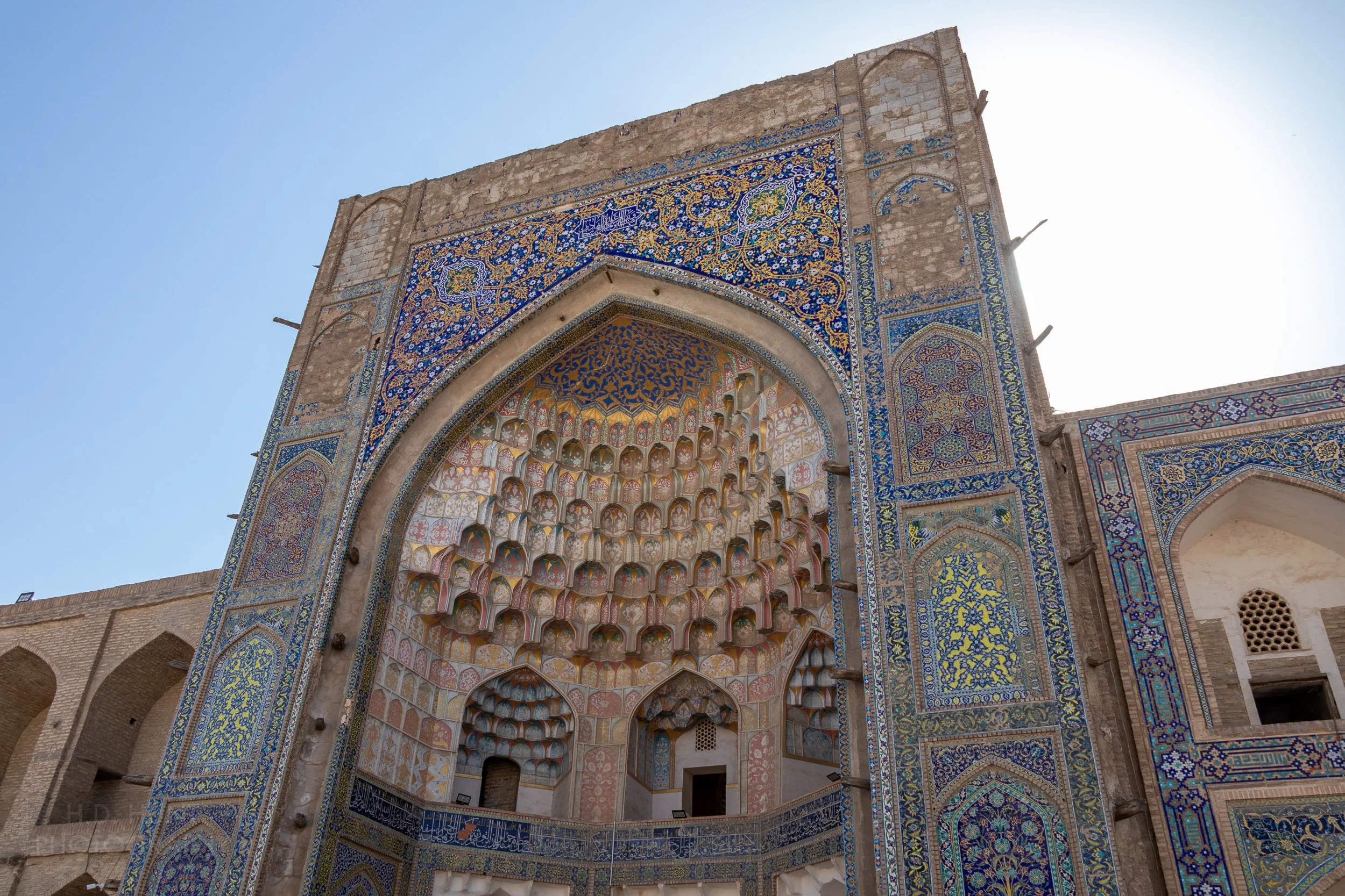 Ornate blue and yellow tiles adorn the iwan of the Abdulaziz Khan Madrasa, which also features an intricate muqarnas, Bukhara, Uzbekistan.