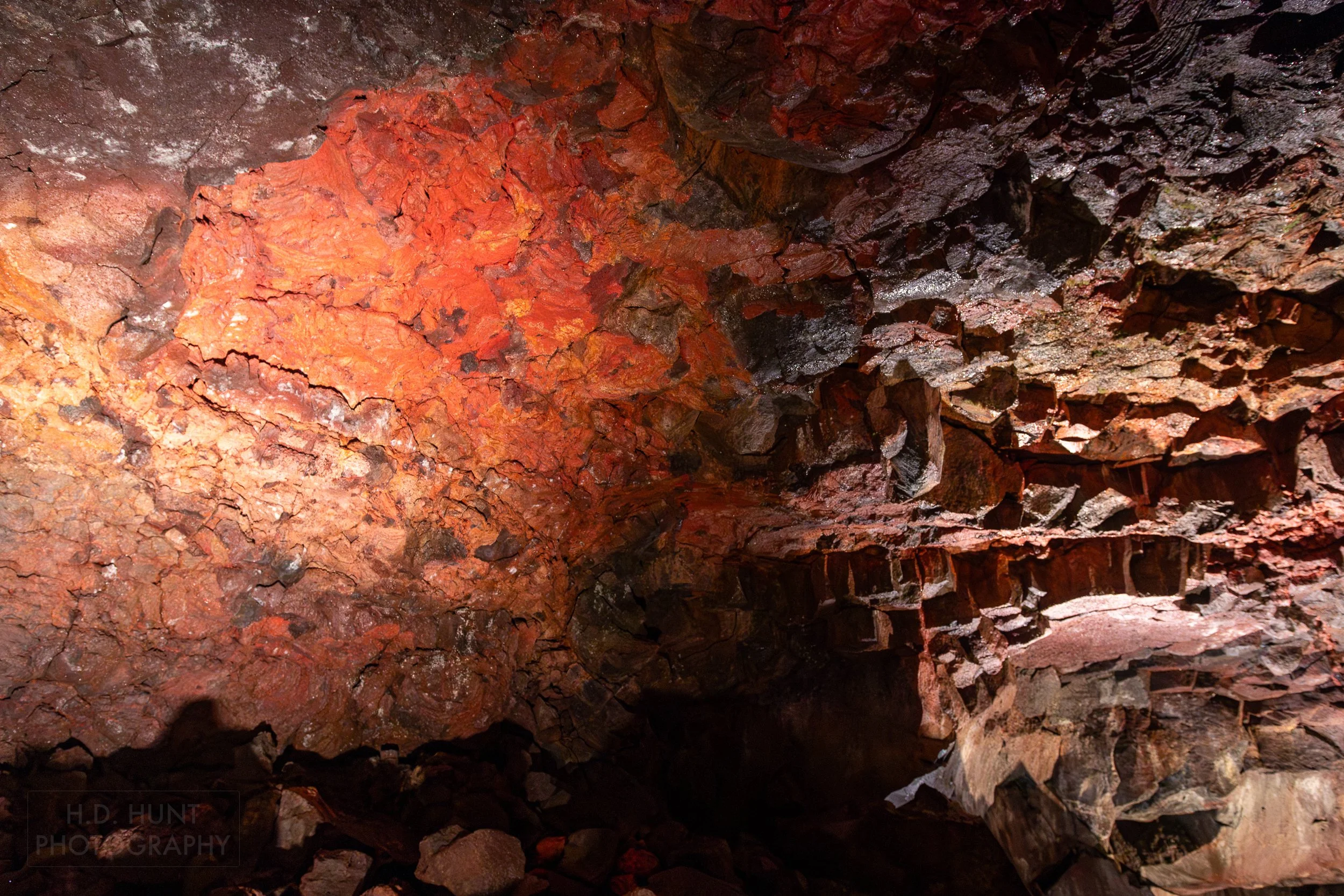 Bright red rock is seen on a dark colored wall within the lava tube Raufarhólshellir, Iceland.