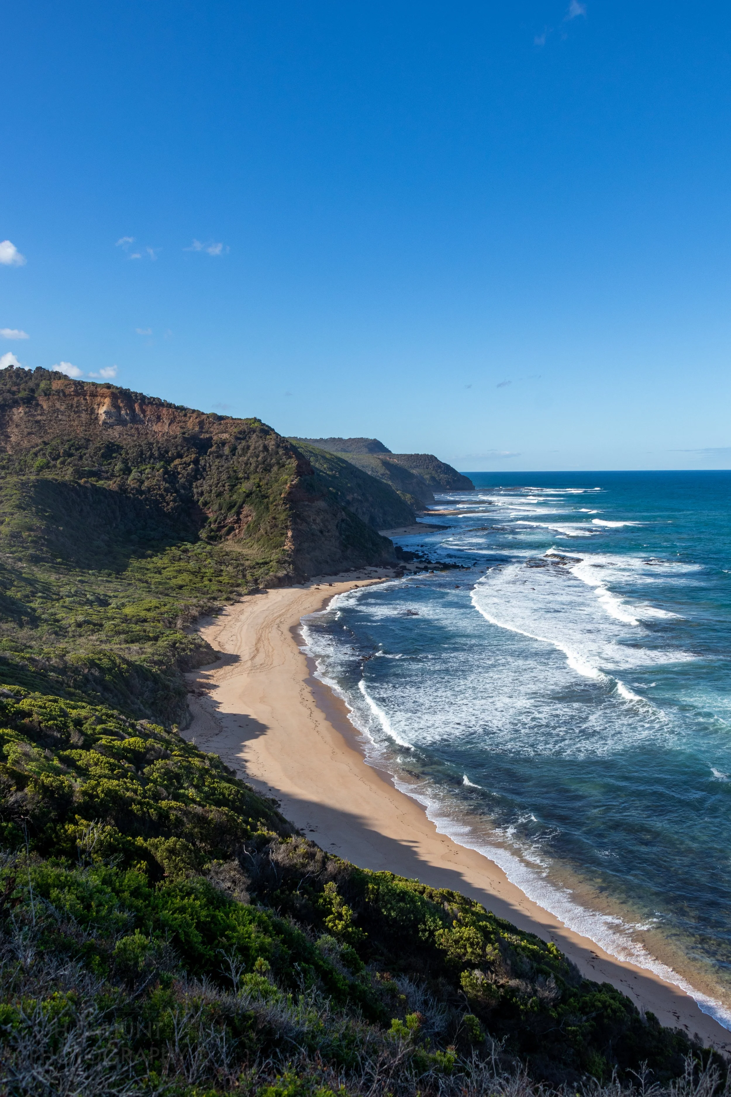 Large whitecap waves from the blue ocean crash against the cliffs along The Great Ocean Walk, Victoria, Australia.