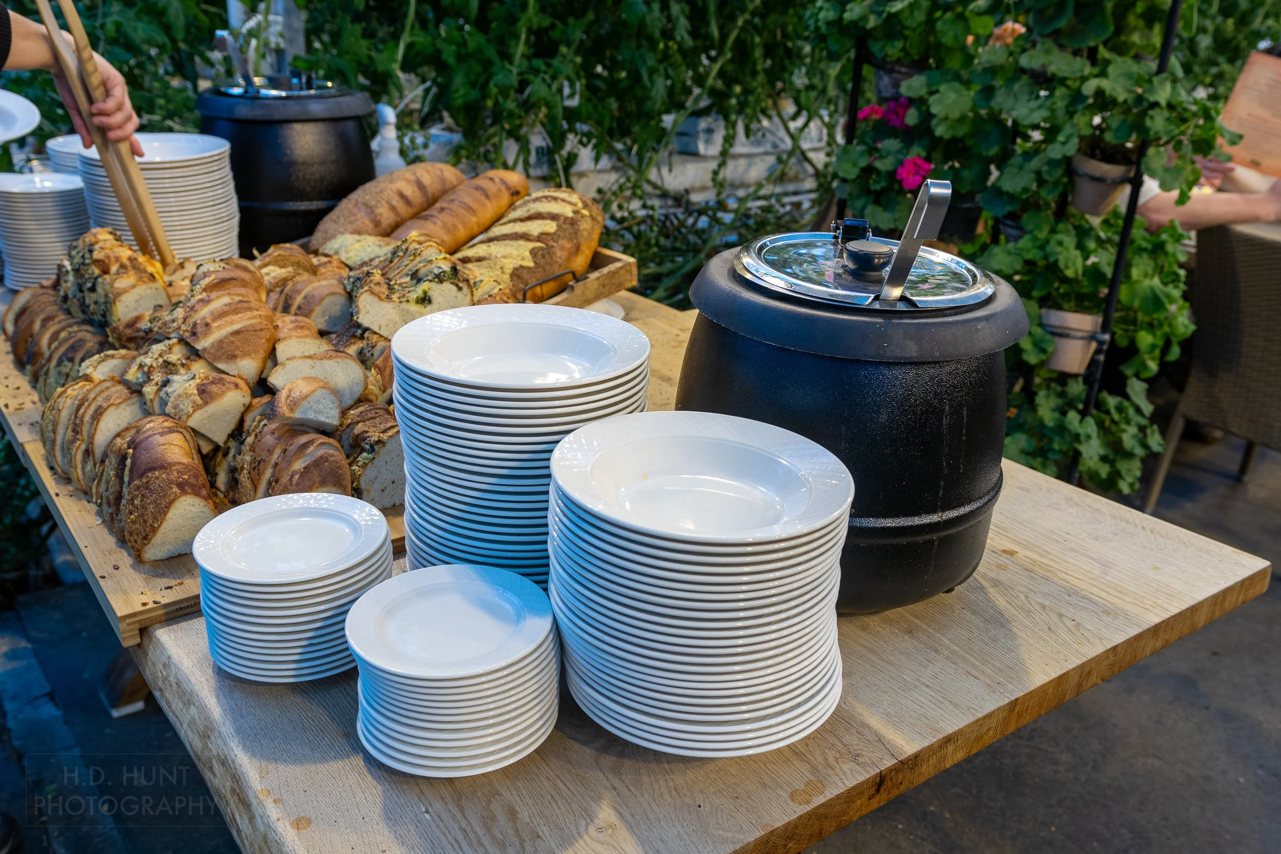 White bowls and plates, an assortment of bread, and two vats of tomato soup sit atop a table at Friðheimar, Reykholt, Iceland.