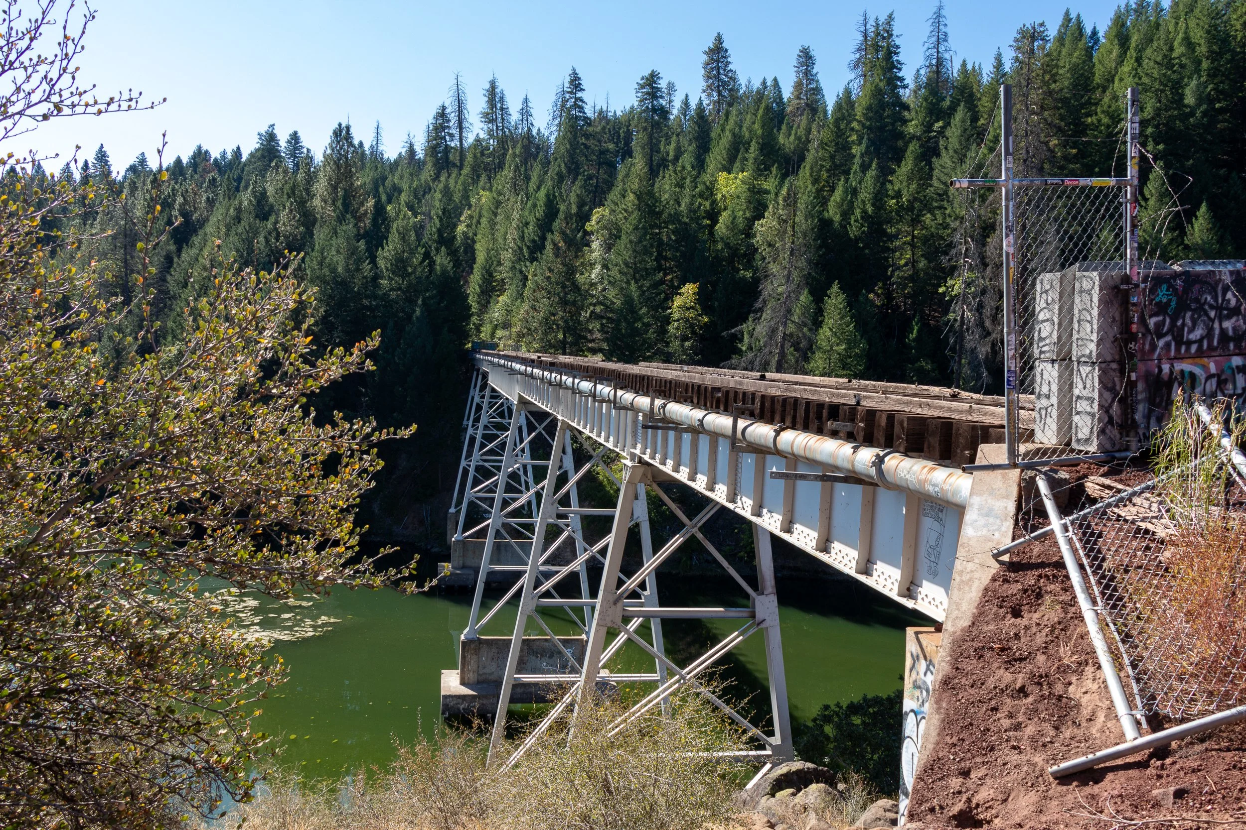 A white railroad trestle - commonly referred to as the Stand By Me Bridge - spans a green-colored river, California, United States.