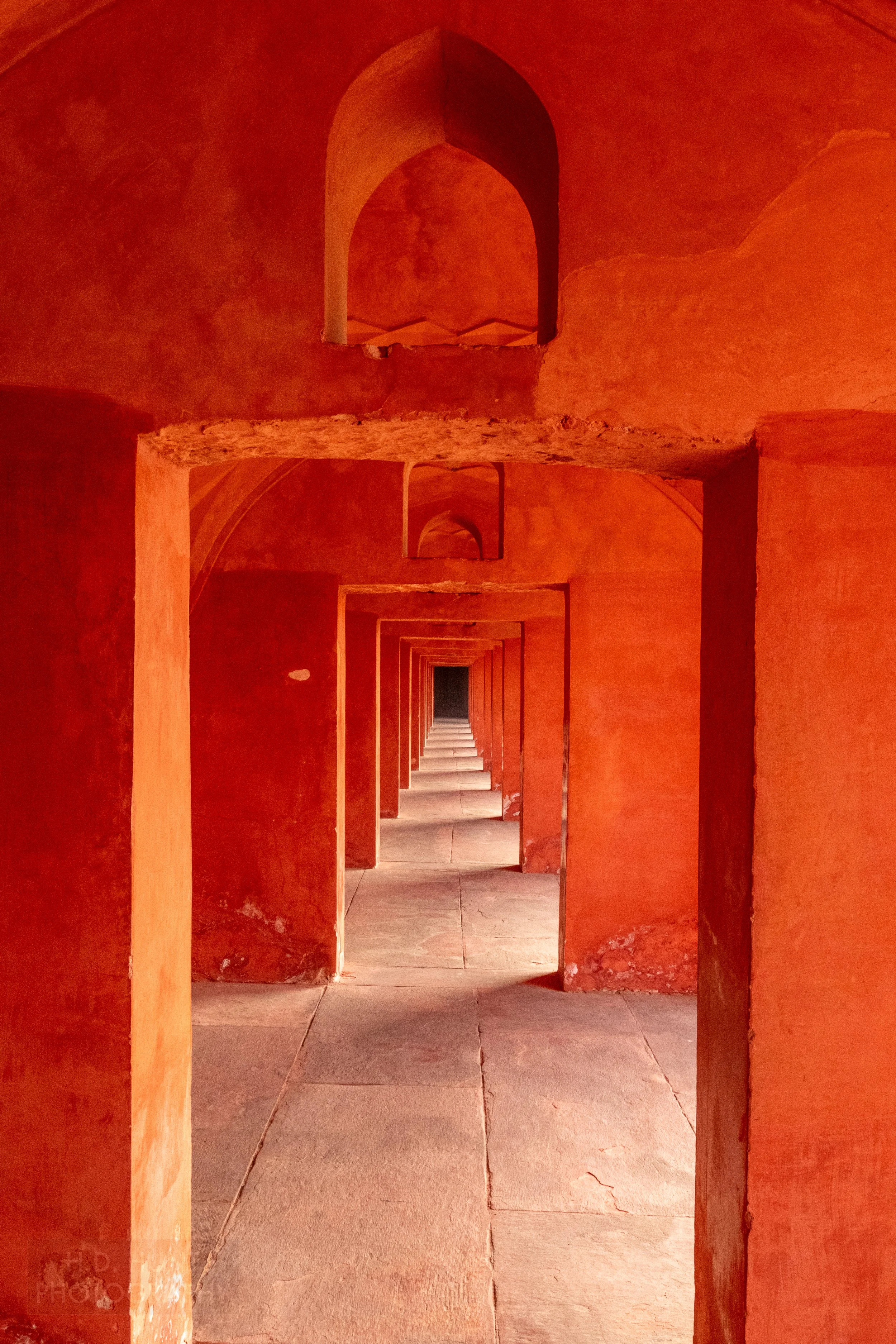 Several archways with bright red paint form a corridor outside Taj Mahal, Agra, India.