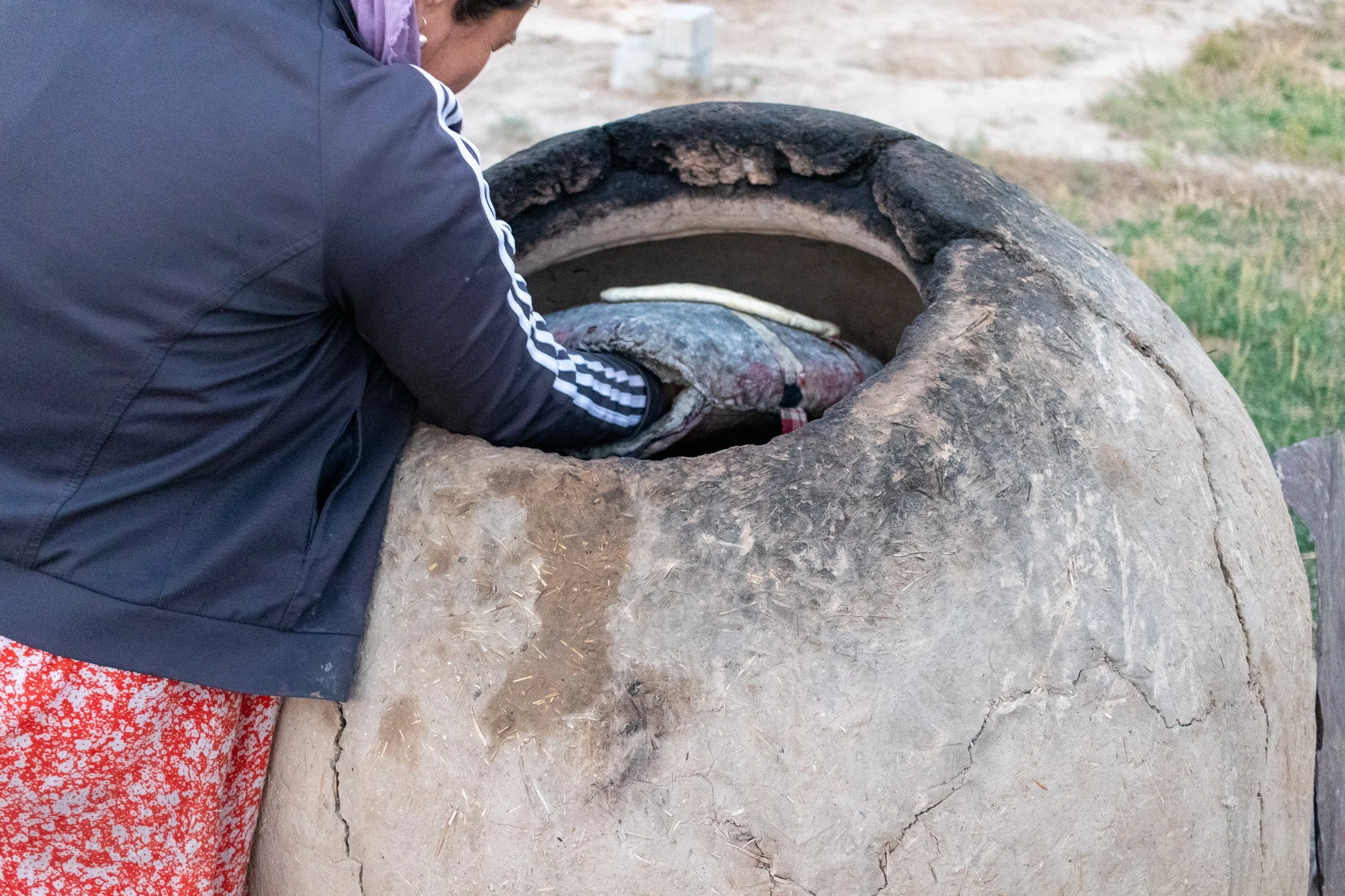 A woman places bread dough into a tandoor oven in Yangikazgan, Uzbekistan.