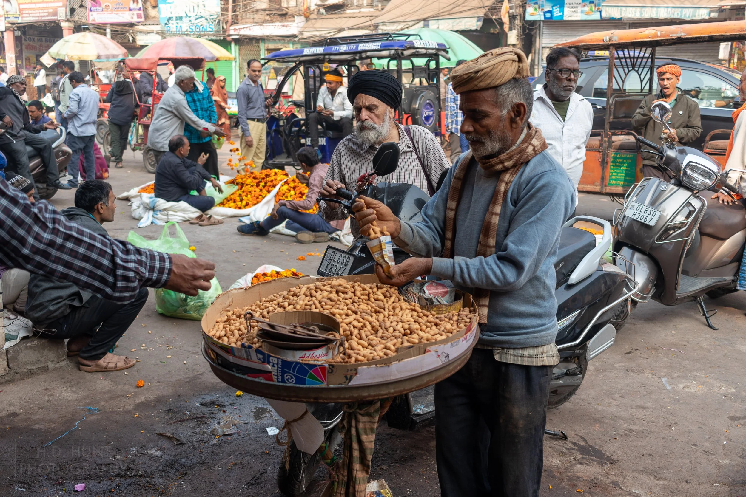 A man selling nuts from a large round tray, Chandni Chowk, Delhi, India.
